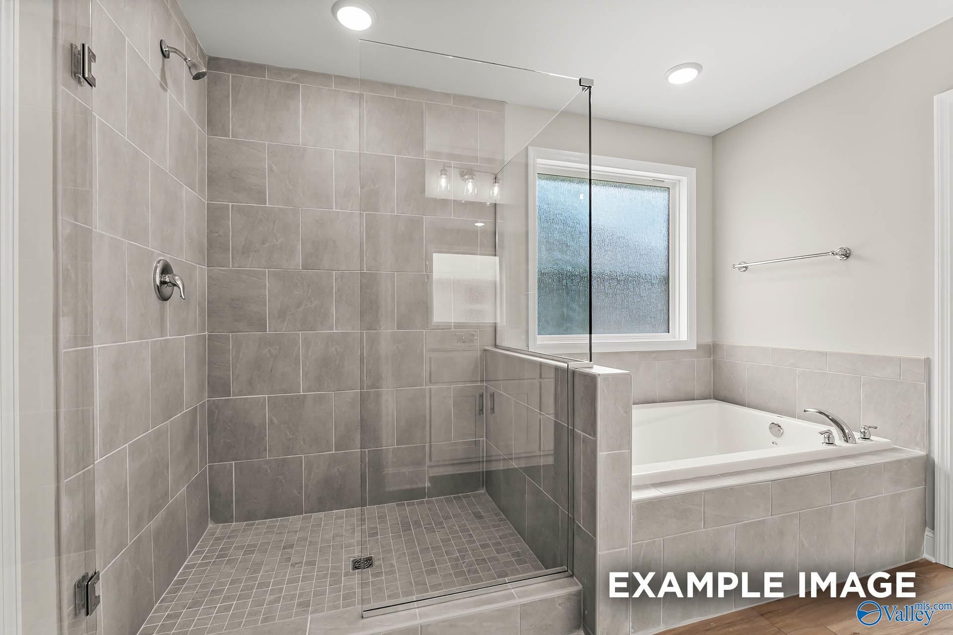 Modern master bathroom featuring gray tiled walk-in shower and soaking tub in Davidson Homes Chelsea B, Toney, Alabama