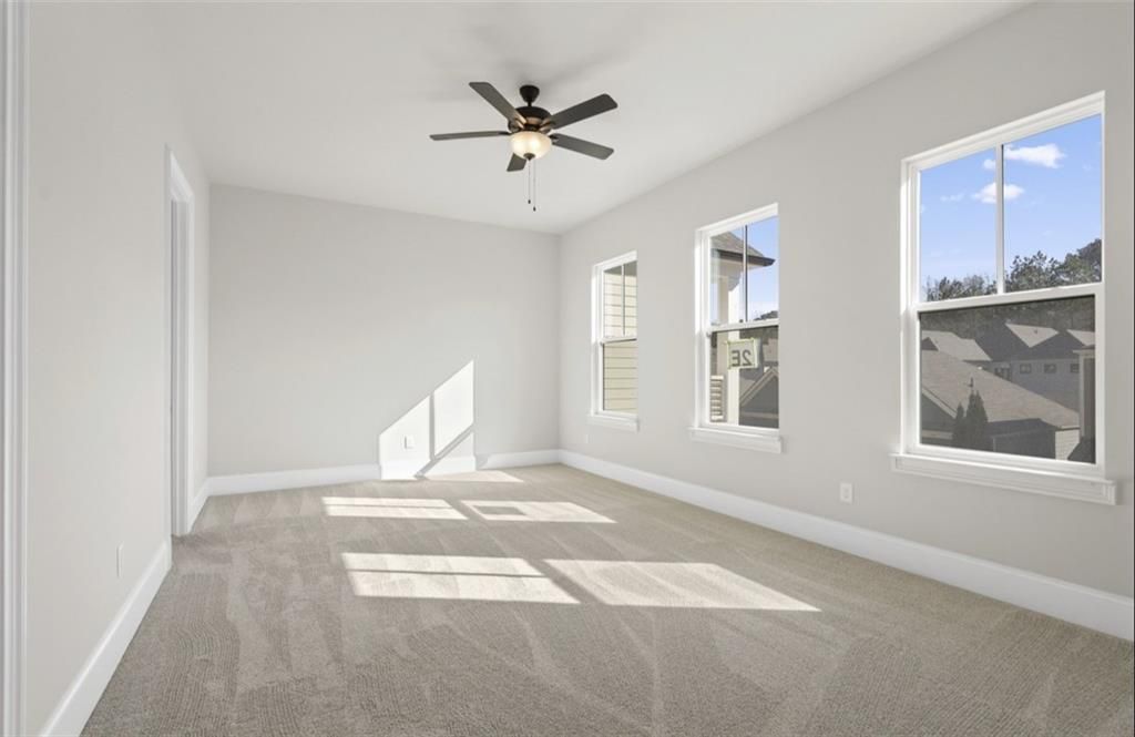 Bright bedroom with beige carpet, large windows, ceiling fan in Davidson Homes The Seaside A, Woodstock, Georgia