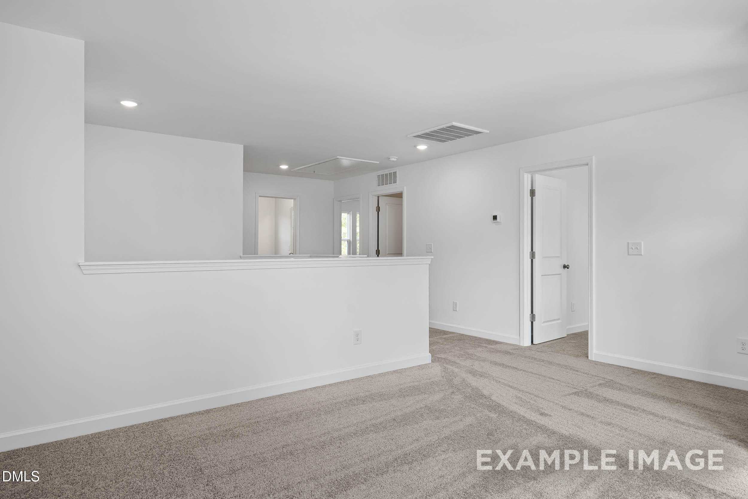 Bright upstairs hallway with white railing overlook and beige carpet in 4-bedroom The Willow D home, Zebulon, NC
