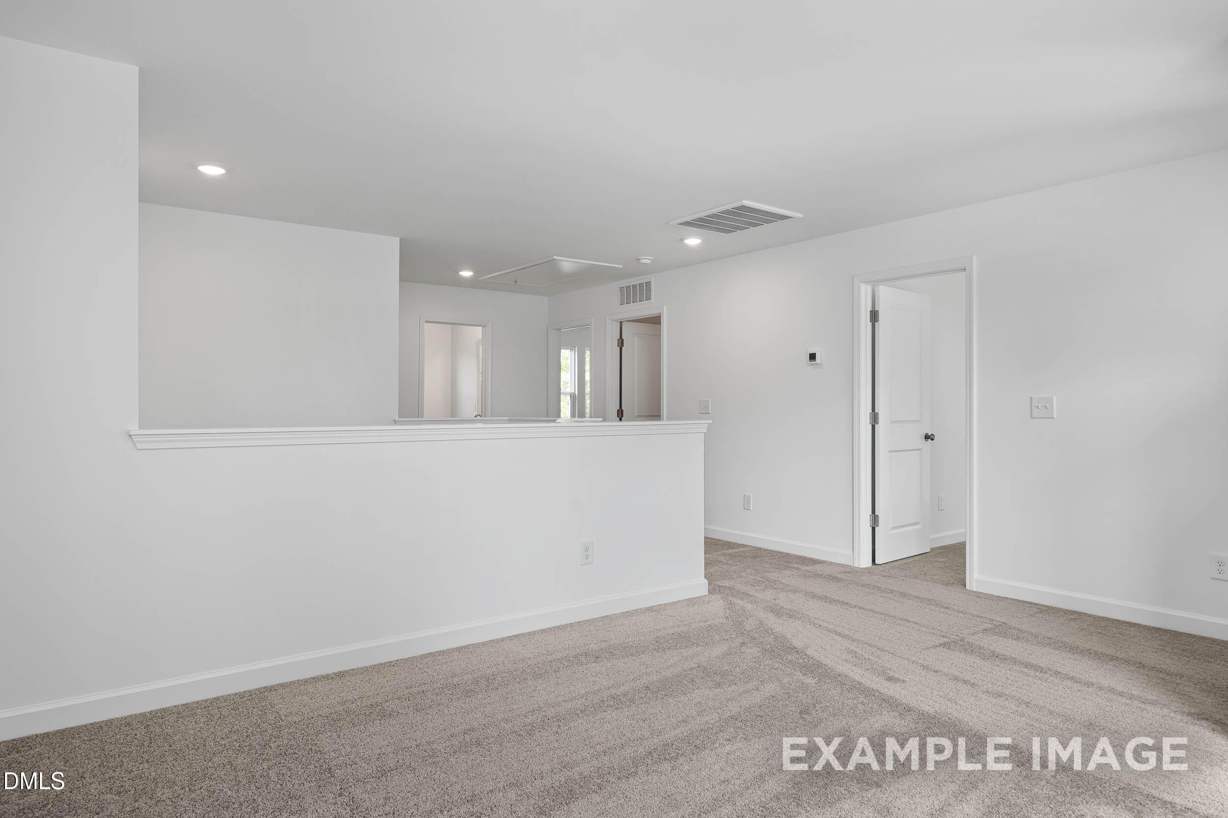 Bright upstairs hallway with white walls, beige carpet, and open balustrade in Davidson Homes The Willow D, Zebulon, NC