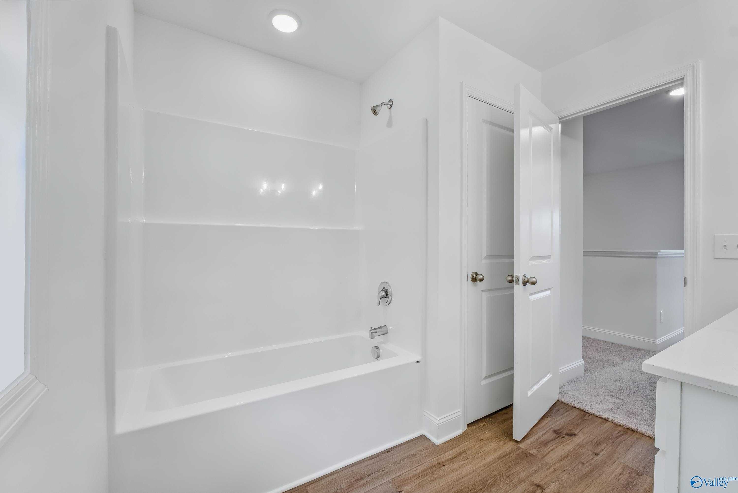Spacious master bathroom with white tiled shower, soaking tub, and walk-in closet doors in Davidson Homes The Shelby A, Arab, Alabama