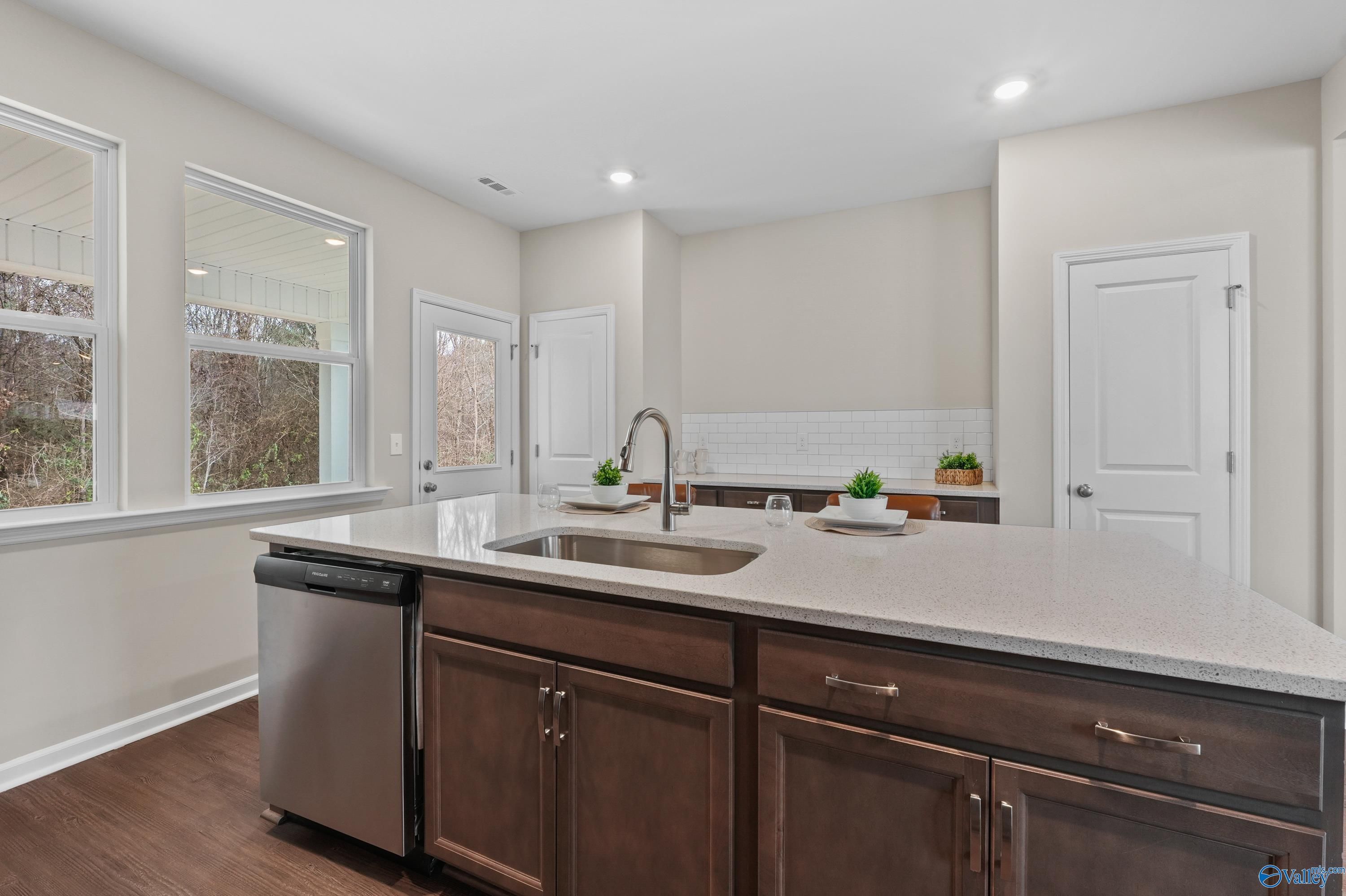 Modern kitchen with large island, quartz counters, stainless dishwasher, and shaker cabinets in The Stella by Davidson Homes, Hazel Green, AL