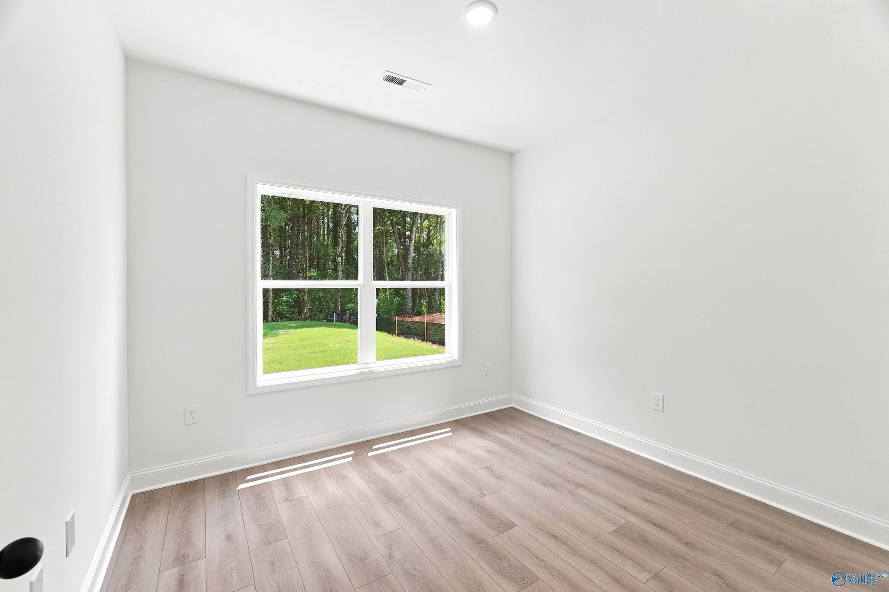 Bright bedroom with wood-look flooring and backyard view in The Shelby B floor plan at Jaguar Hills, Huntsville, Alabama.