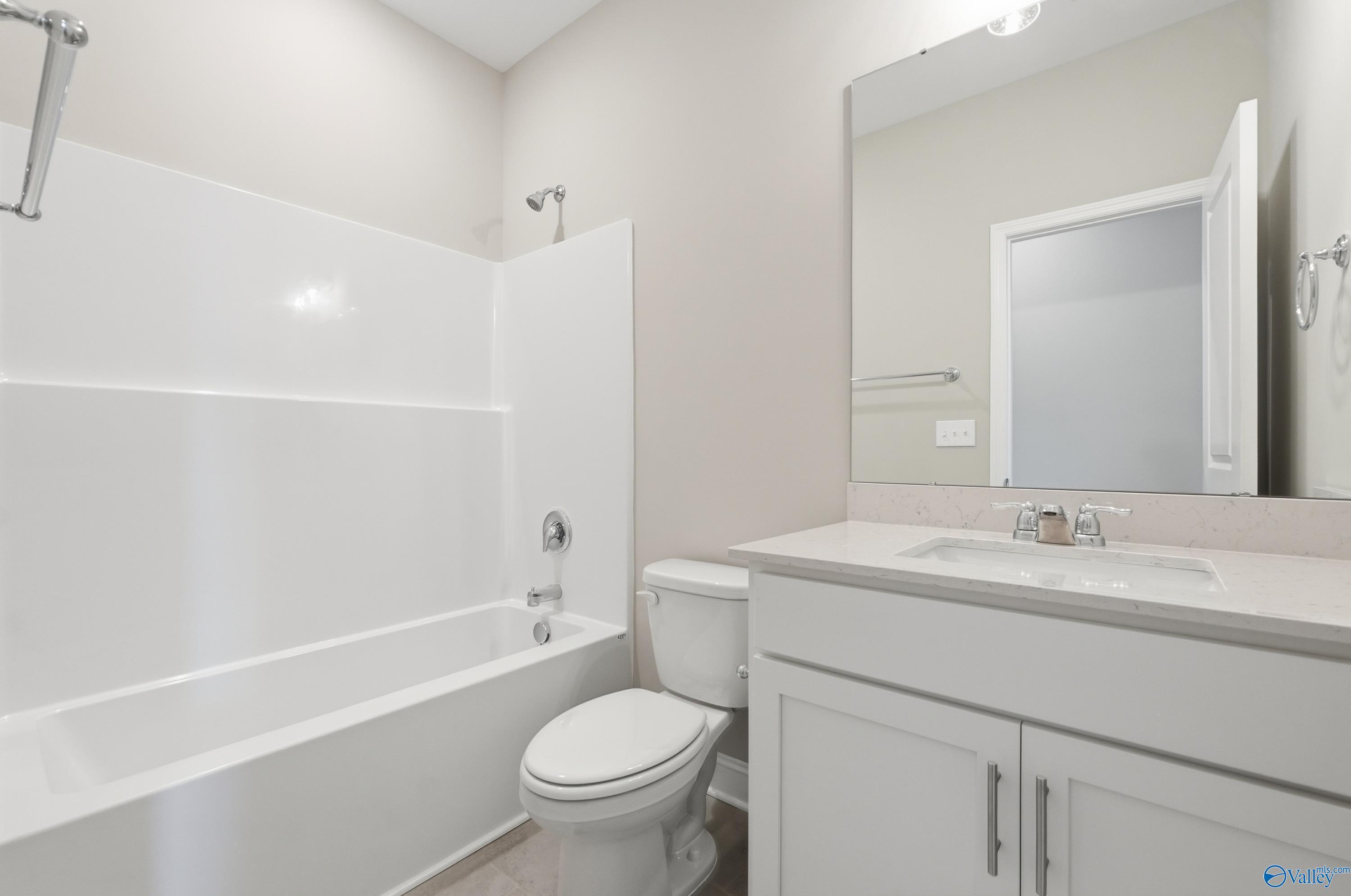 Bright guest bathroom featuring white bathtub-shower combo, vanity sink, and toilet in Davidson Homes The Rockford, Harvest, Alabama