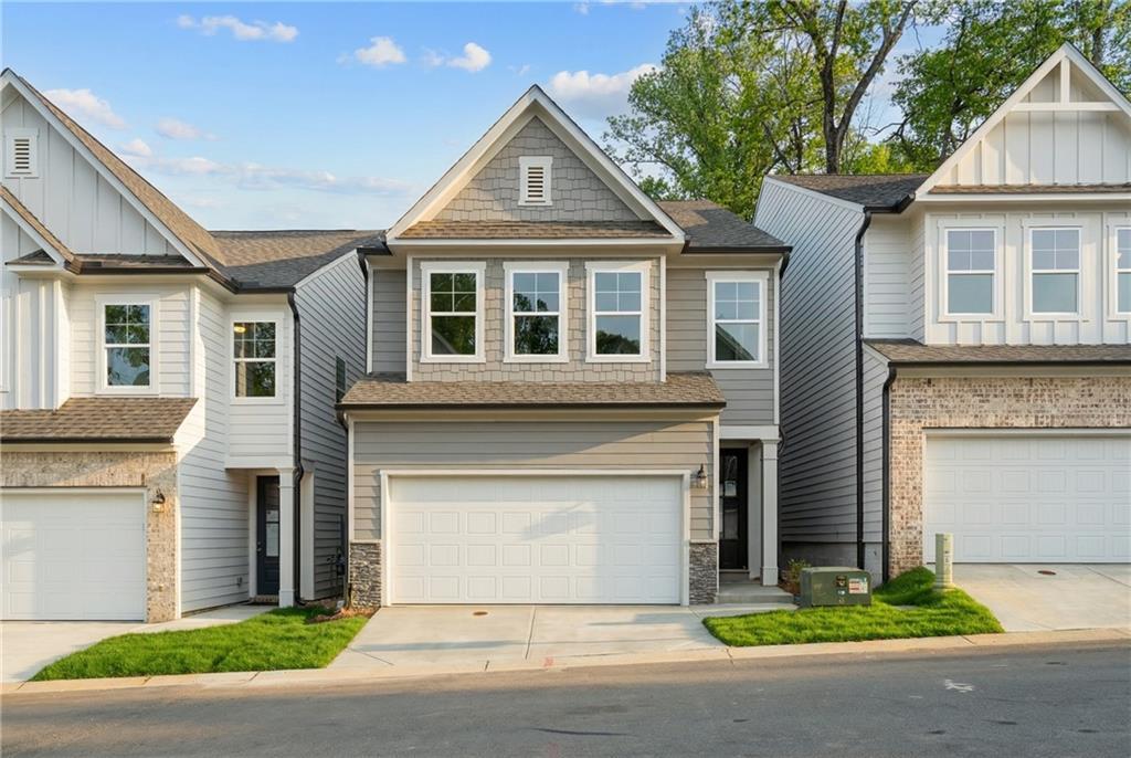 Modern two-story gray townhome with 2-car garage, white trim, and lush front yard in The Village at Shallowford, Kennesaw, Georgia