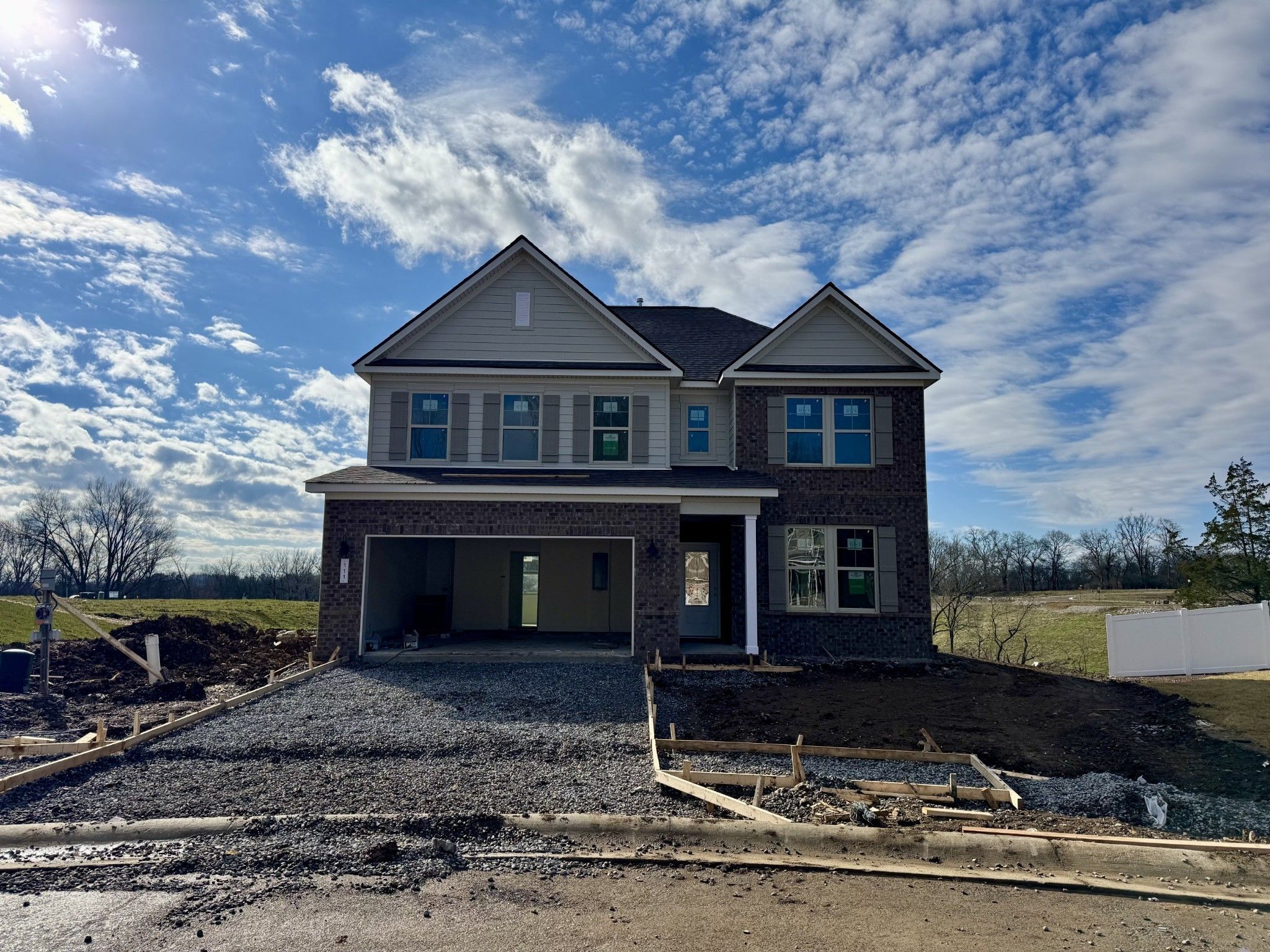 Two-story Willow C home with brick accents, two-car garage, and gravel driveway in Woods Crossing, Gallatin, Tennessee