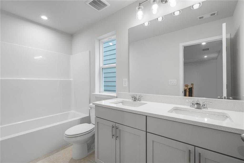 Modern bathroom featuring double gray vanity, glass shower, bathtub, and subway tile in Davidson Homes The Cary A, Kennesaw, GA