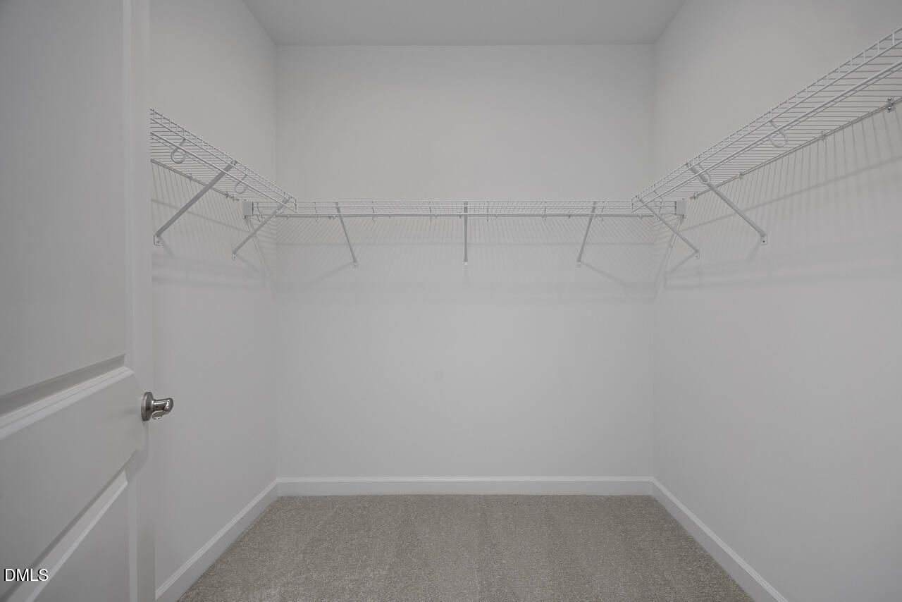 Spacious walk-in closet with white wire shelving in The Ashport L floor plan at Sage on North Main, Wake Forest, NC.