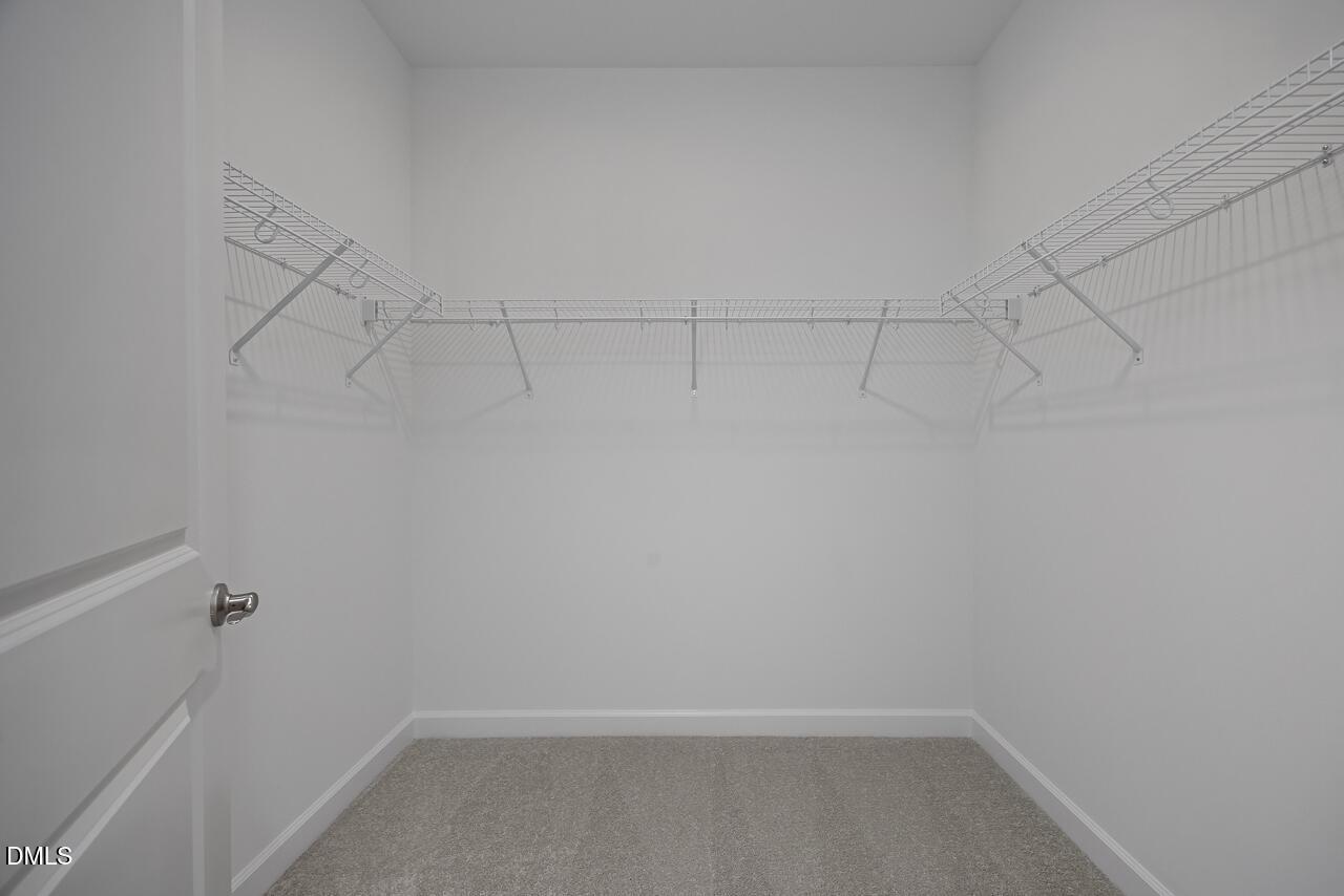 Spacious walk-in closet with white wire shelving in The Ashport L floor plan at Sage on North Main, Wake Forest, NC.