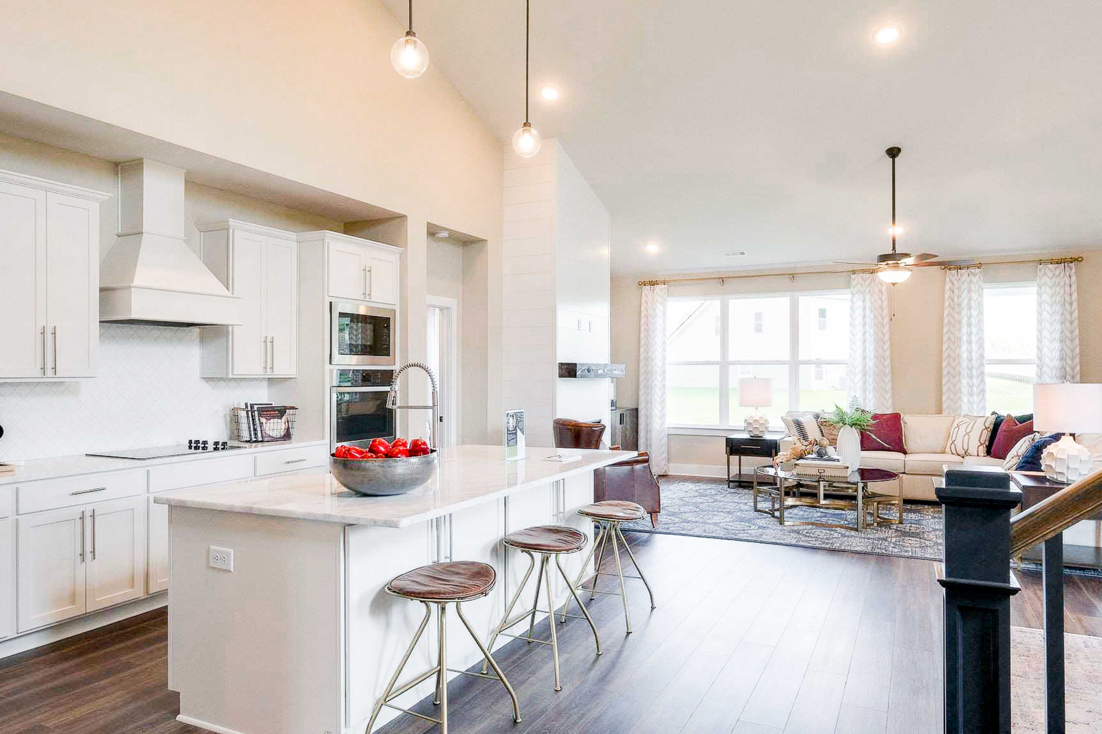 Open-concept kitchen and living room at The Meadows in Smyrna TN with white island, bar stools, hardwood floors, and sectional sofa