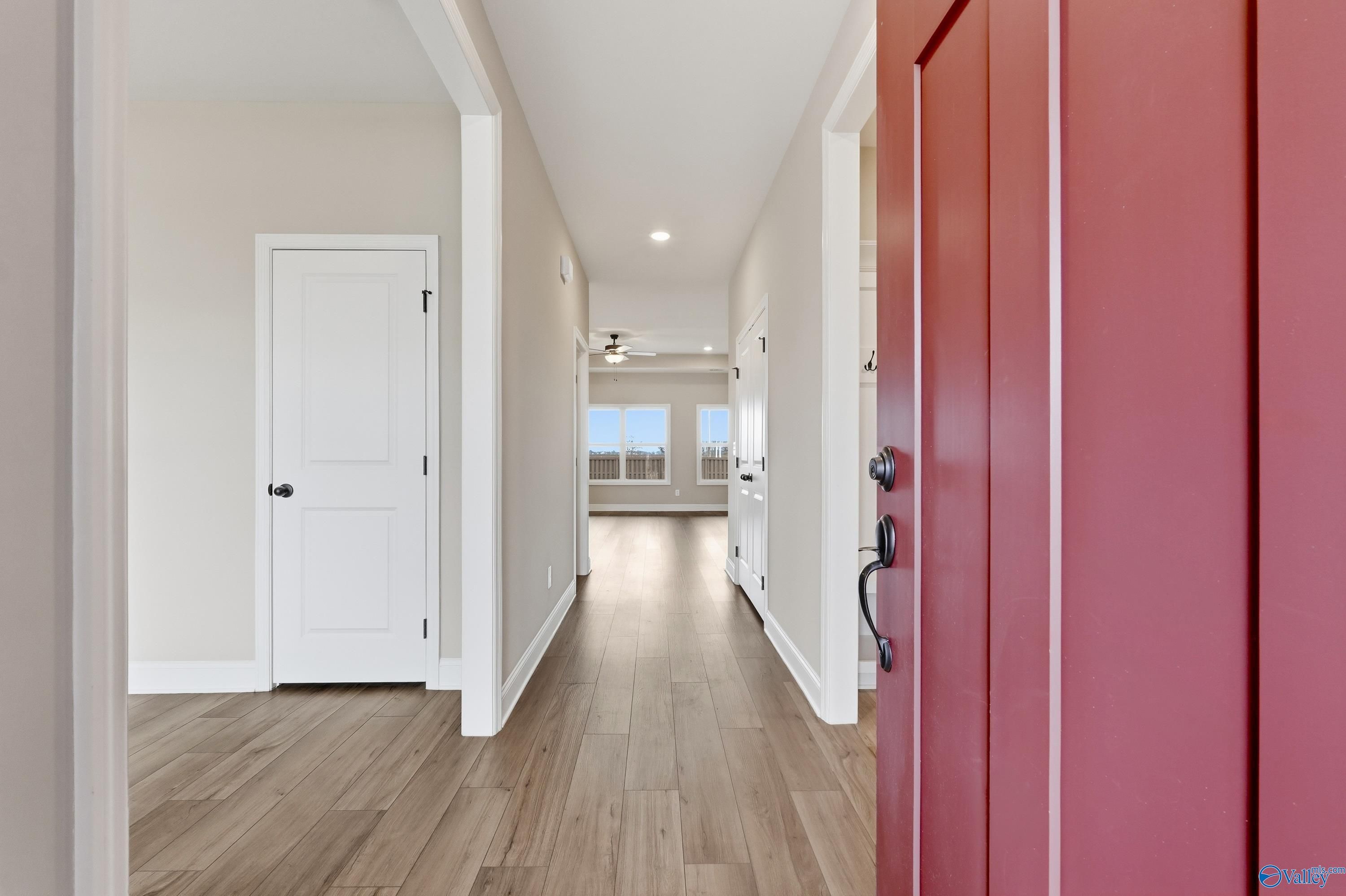 Spacious hallway with hardwood floors, white doors, and red entry in Davidson Homes The Rockford C, Athens AL