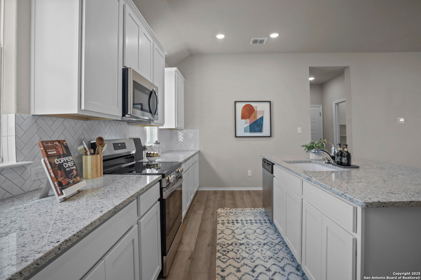 Modern kitchen with white shaker cabinets, granite countertops, stainless appliances, and subway tile backsplash in The Collin B, Seguin, Texas