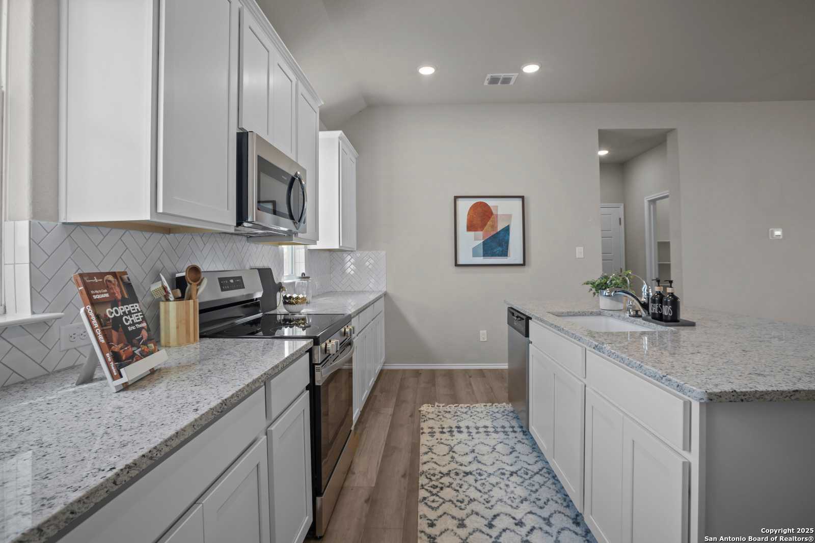 Modern kitchen with white shaker cabinets, granite countertops, stainless appliances, and subway tile backsplash in The Collin B, Seguin, Texas