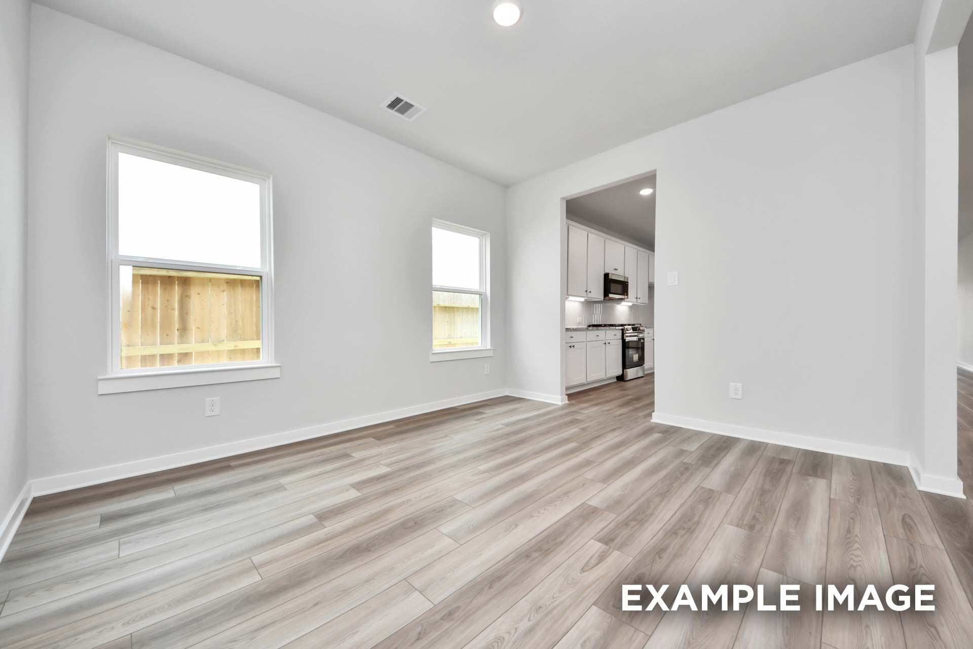 Bright open-concept dining area in The Sorrento floor plan with wood-look flooring and view into the modern kitchen.