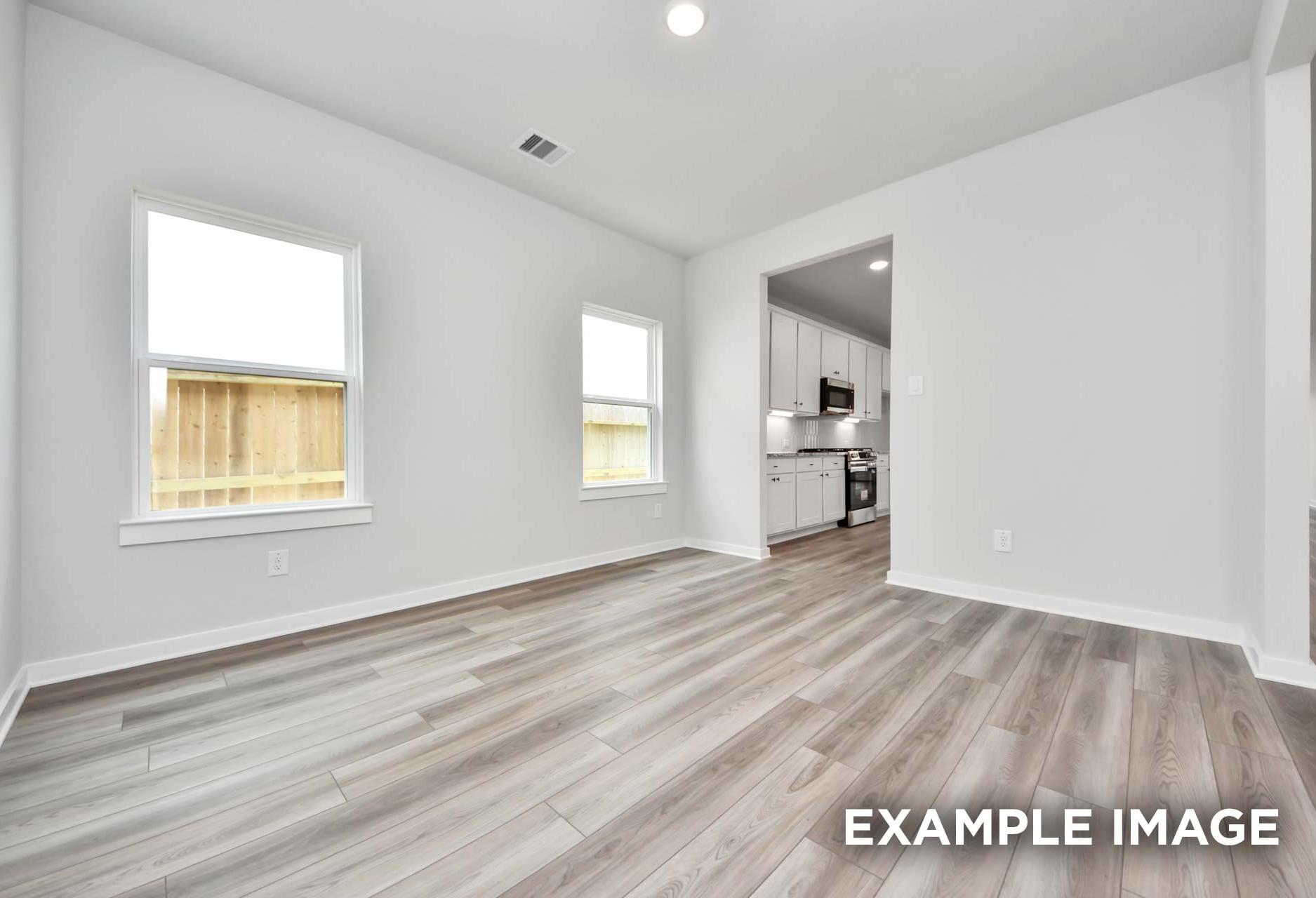 Bright open-concept dining area in The Sorrento floor plan with wood-look flooring and view into the modern kitchen.
