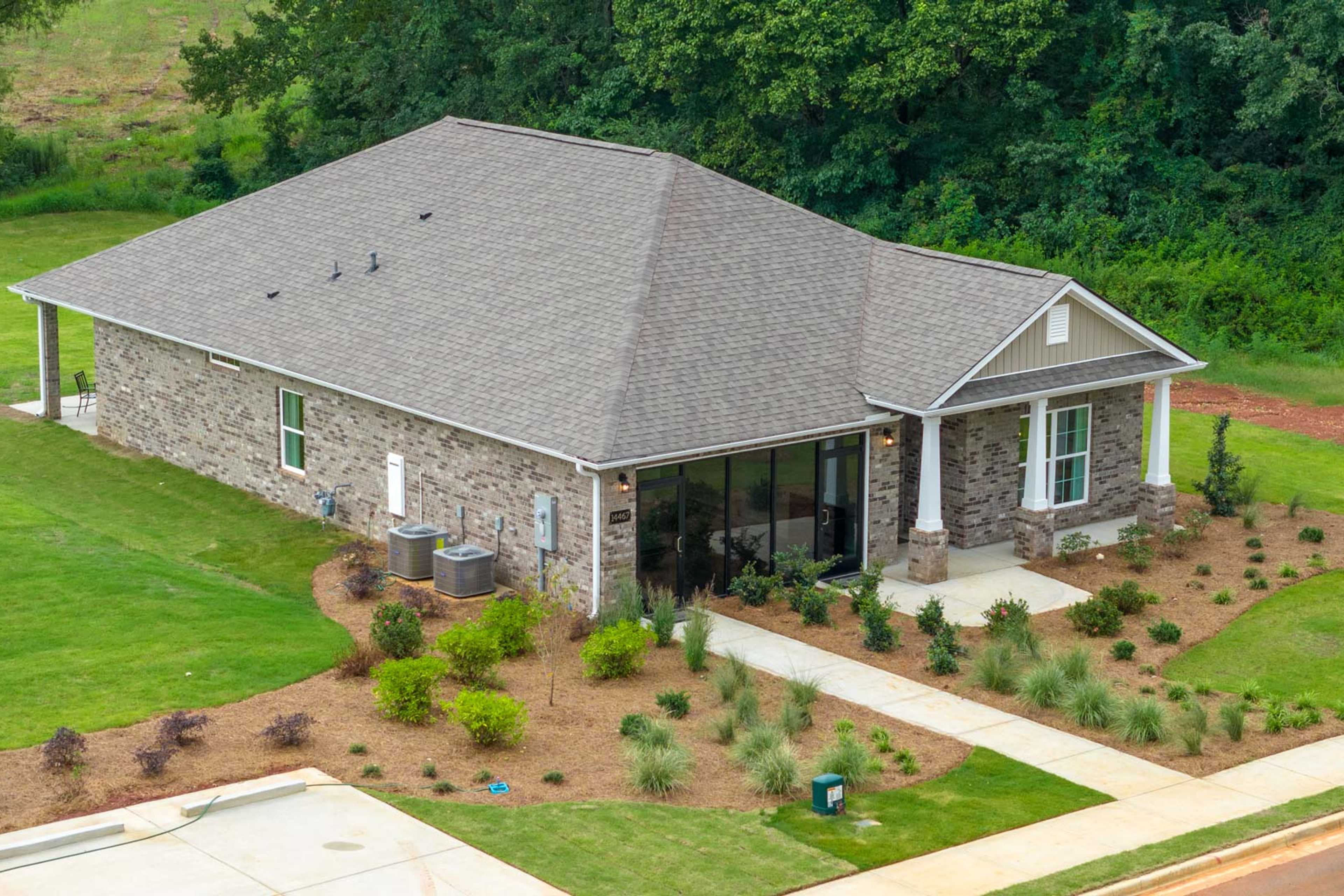 Modern ranch-style home exterior at The Meadows in Athens, Alabama with brick accents, covered porch and lush landscaping
