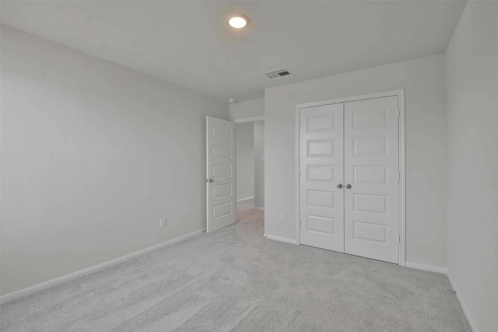 Spacious secondary bedroom with walk-in closet, gray walls, and carpeted floors in Davidson Homes The Tierra A, Dayton Texas