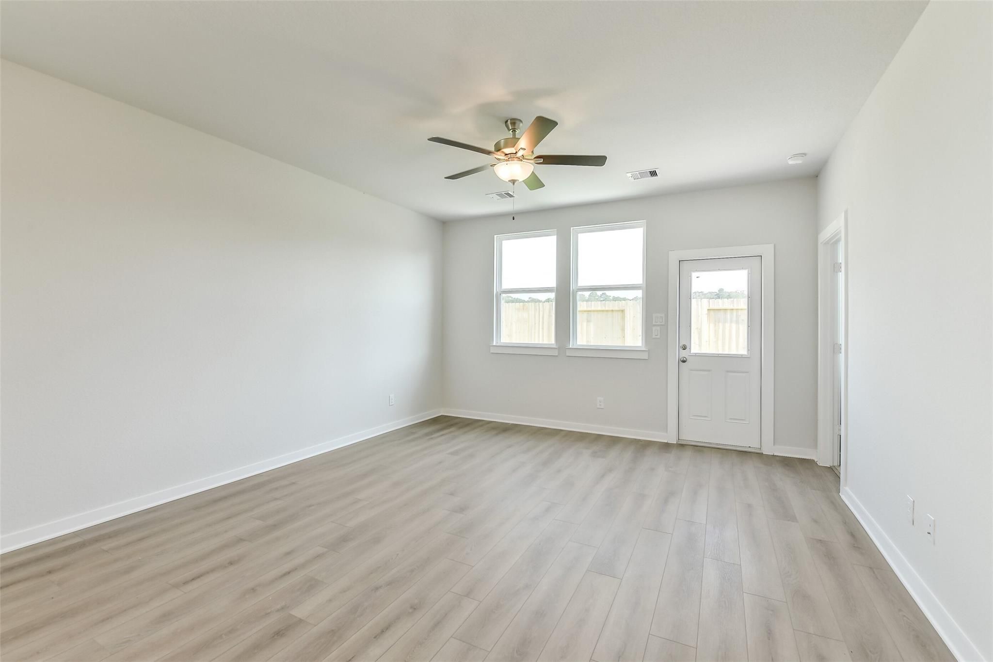 Bright living room with ceiling fan, large windows, laminate flooring in Davidson Homes The Colorado F, Cleveland, Texas