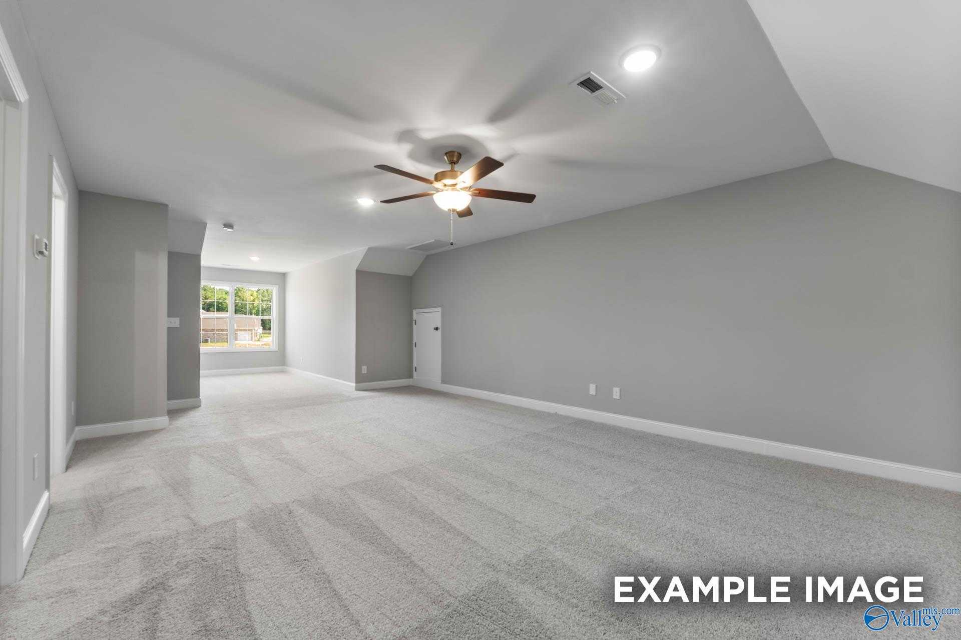 Spacious bonus room with gray walls, beige carpet, ceiling fan, and large windows in Davidson Homes The Rockford D, Hazel Green, Alabama
