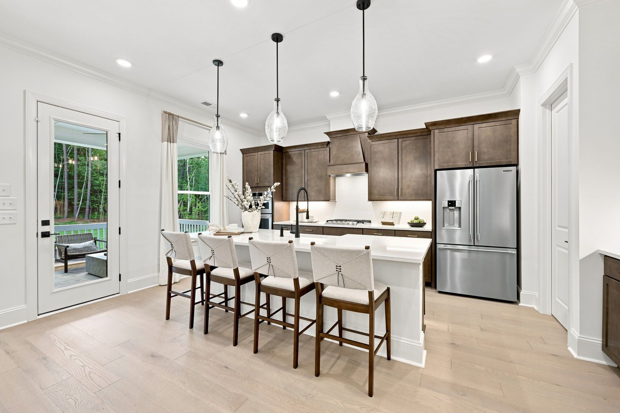 Gourmet kitchen in The Barrington C featuring a large quartz island, dark wood cabinetry, and stainless steel appliances.