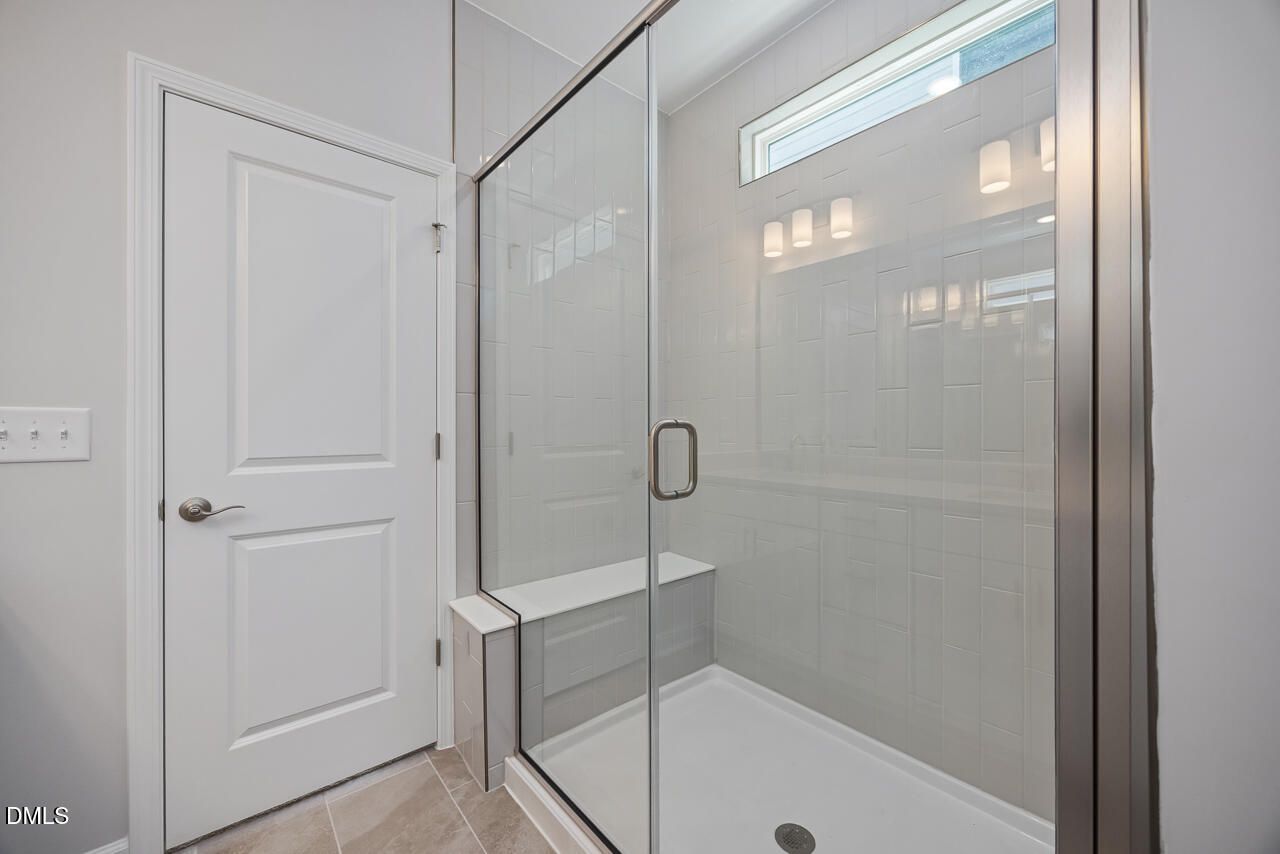 Modern walk-in tile shower with built-in bench in The Ashport L floor plan at Sage on North Main, Wake Forest, NC.