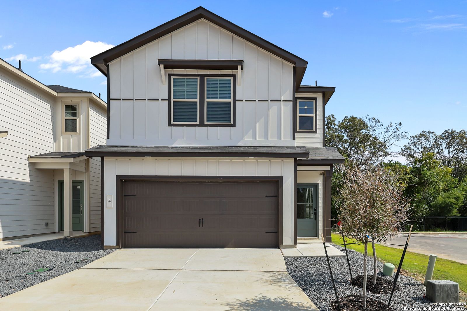 Modern two-story home with white siding, brown trim, 2-car garage, and driveway in Cedar Heights, San Antonio, Texas by Davidson Homes