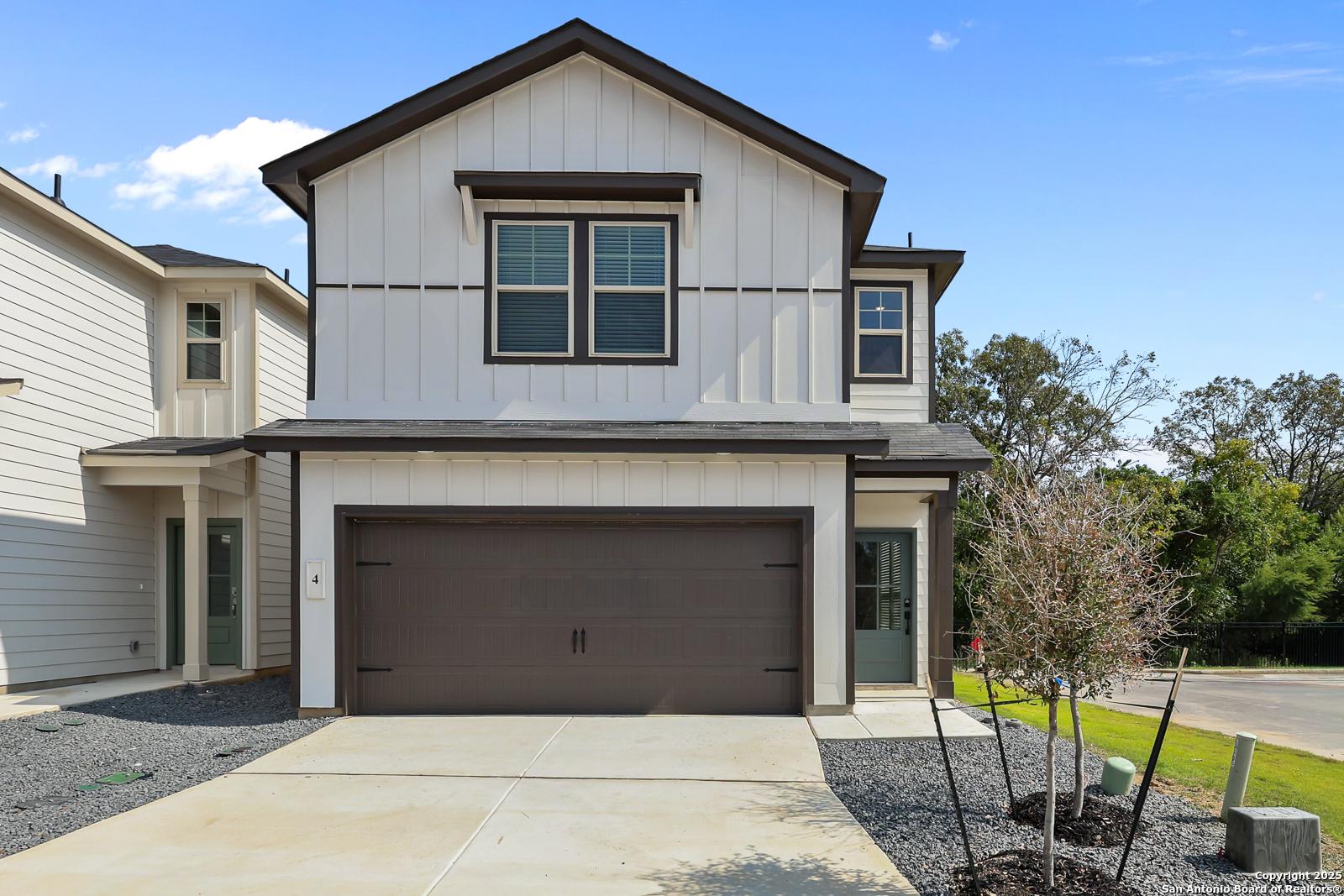 Modern two-story home with white siding, brown trim, 2-car garage, and driveway in Cedar Heights, San Antonio, Texas by Davidson Homes