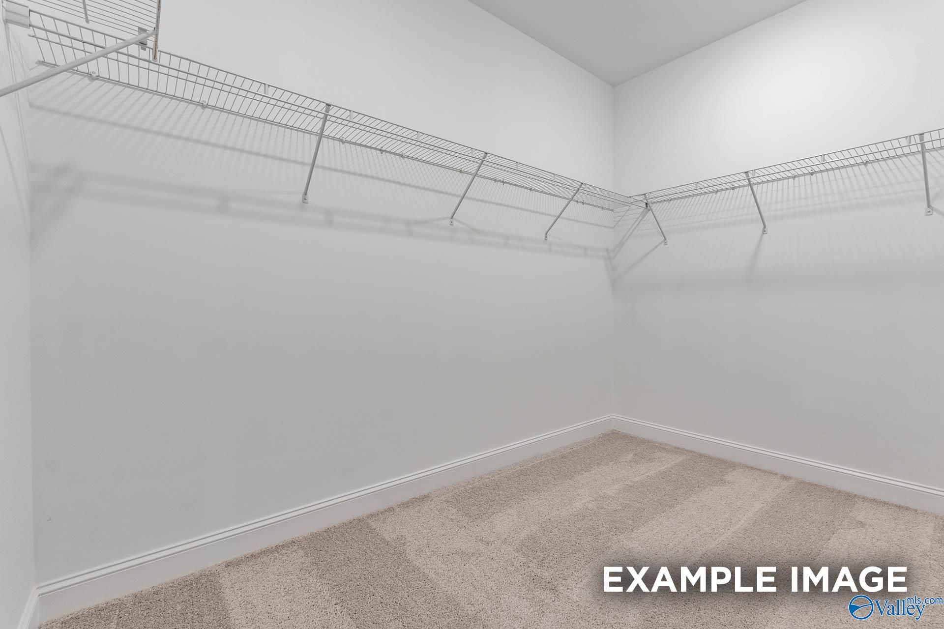 Spacious walk-in closet with wire shelving and white walls in The Emory master suite, Davidson Homes, Toney, Alabama