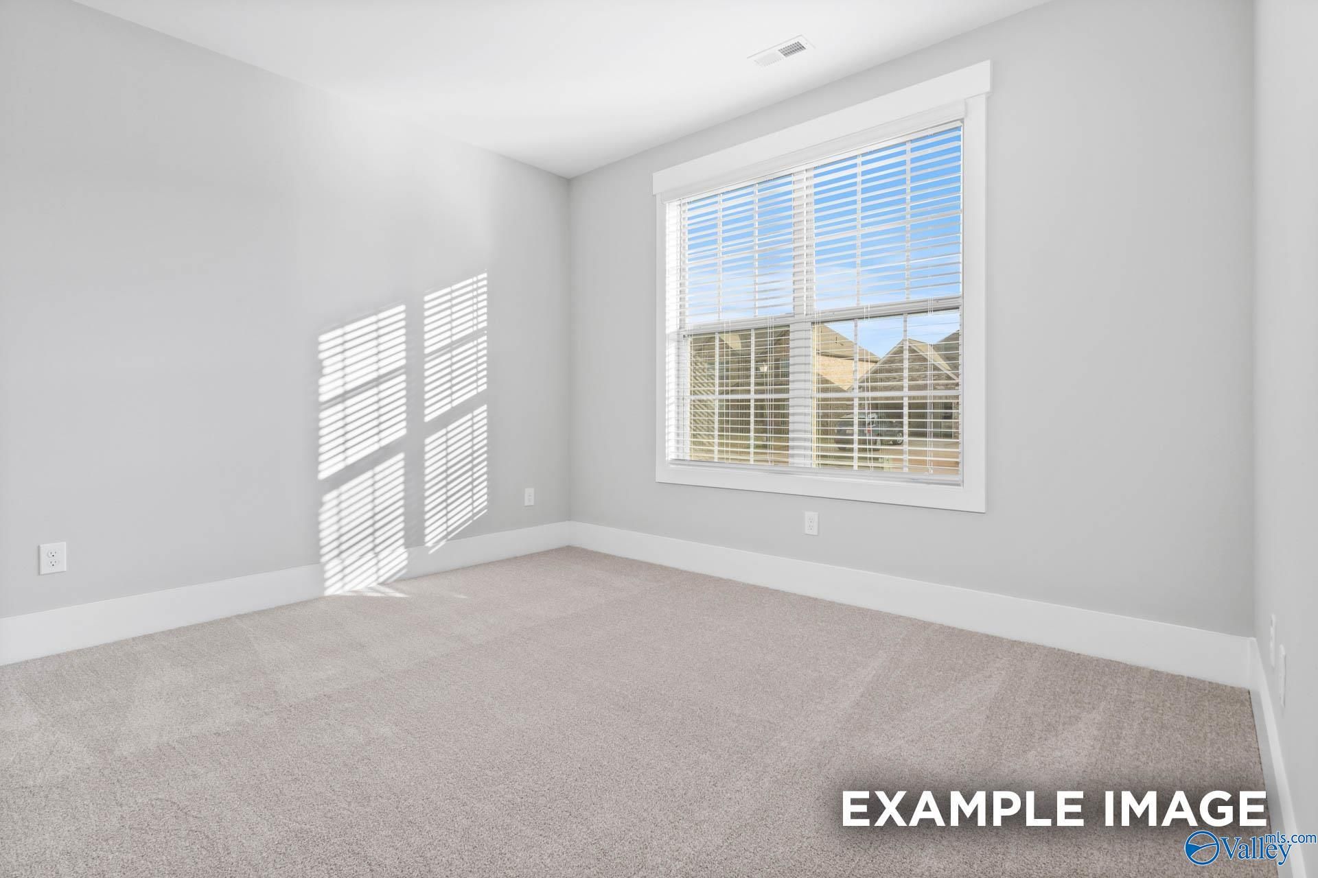Bright secondary bedroom with large window, gray walls, and plush carpet in Davidson Homes The Rockford, Pikes Ridge, Meridianville AL