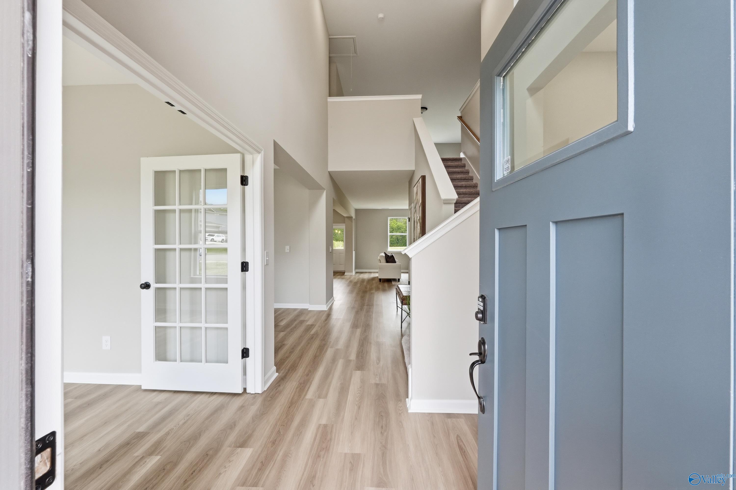 Grand two-story foyer with open French doors, hardwood floors, and sweeping staircase in Davidson Homes The Dorado, Huntsville