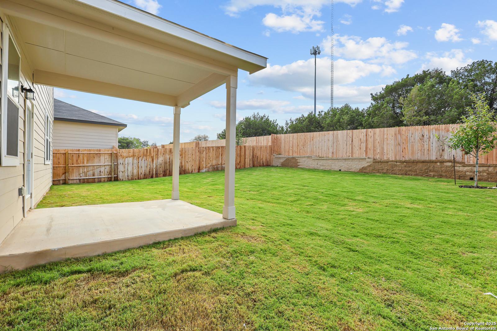 Covered patio with wooden beams overlooking lush green backyard and privacy fence in Davidson Homes The Douglas G, Royal Crest, San Antonio