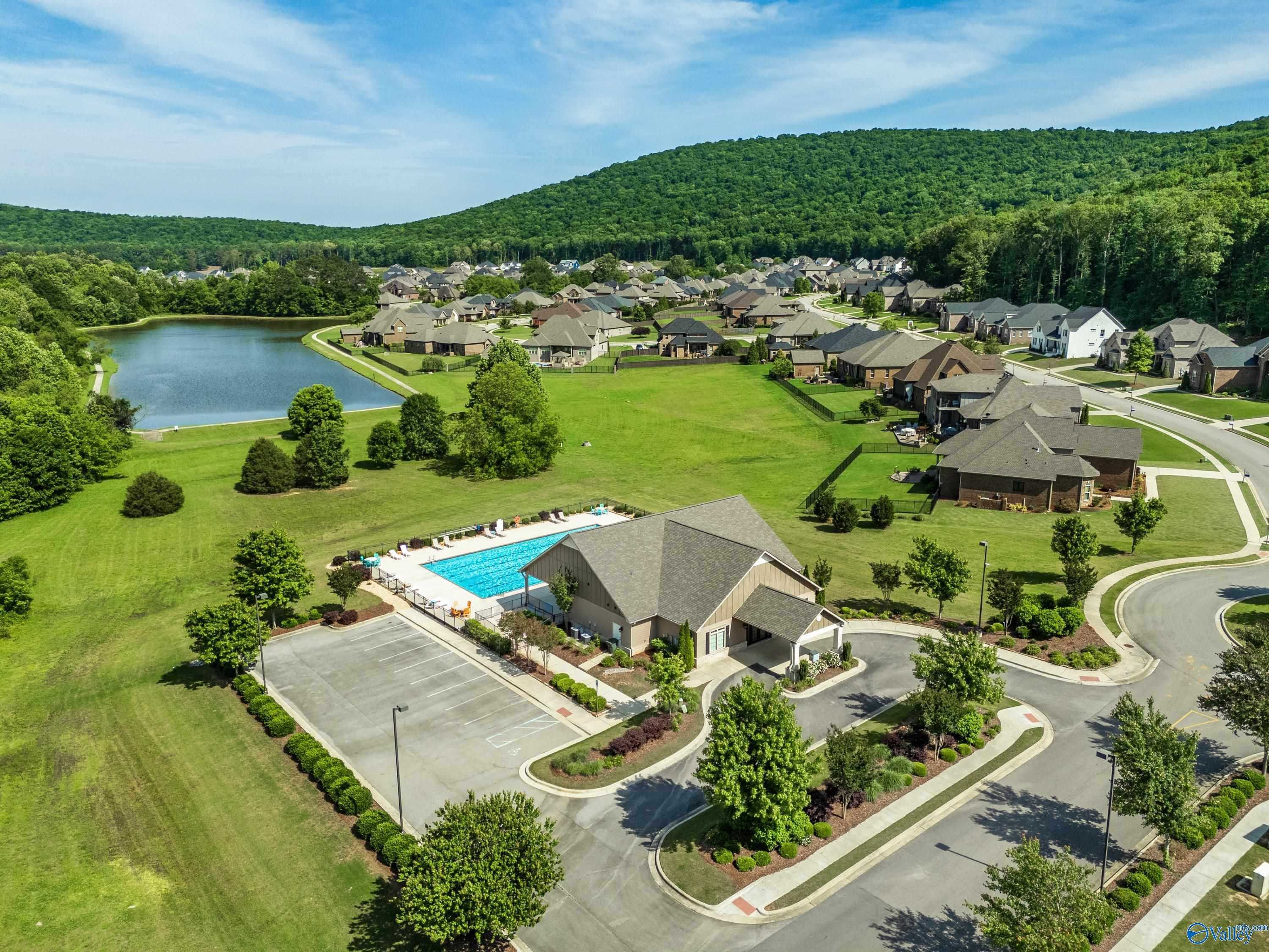 Aerial view of The Meadows at Hampton Cove with community pool, clubhouse, pond, modern homes, and lush hills in Owens Cross Roads, Alabama