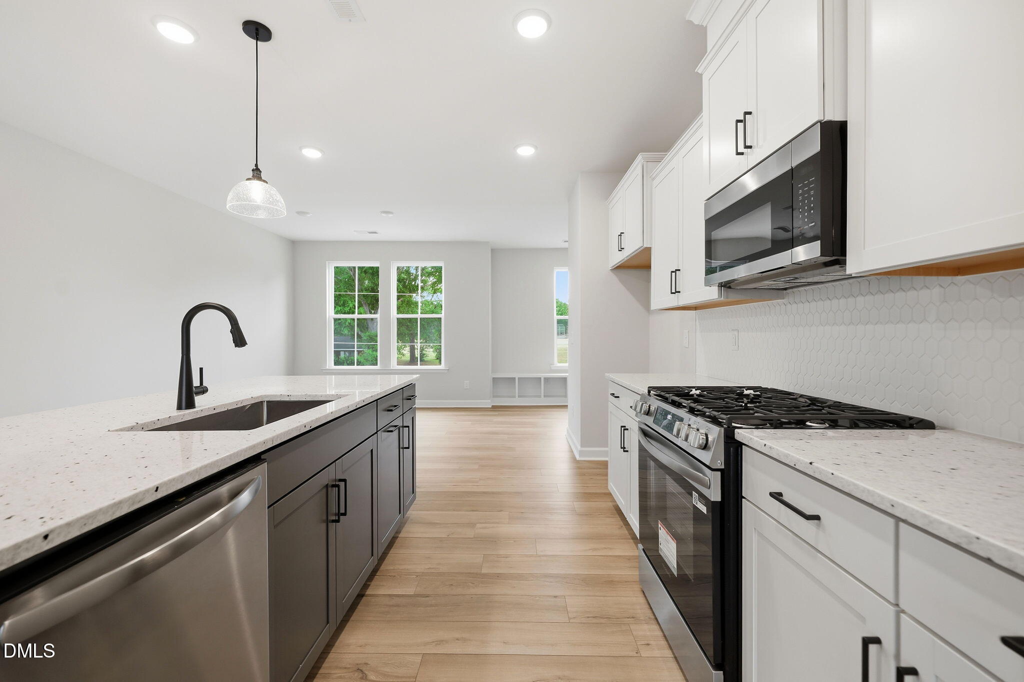 Modern kitchen with white cabinets, granite countertops, and stainless appliances in The Mitchell floor plan, Knightdale, NC.