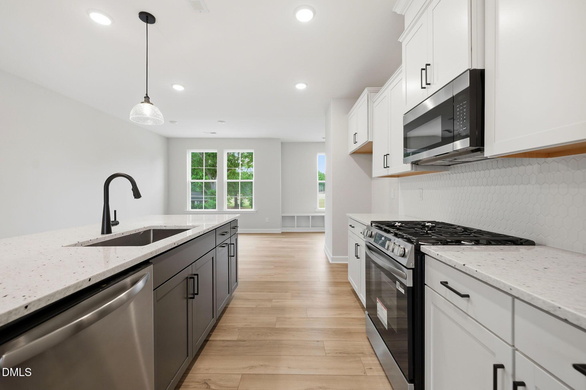 Modern kitchen with white cabinets, granite countertops, and stainless appliances in The Mitchell floor plan, Knightdale, NC.