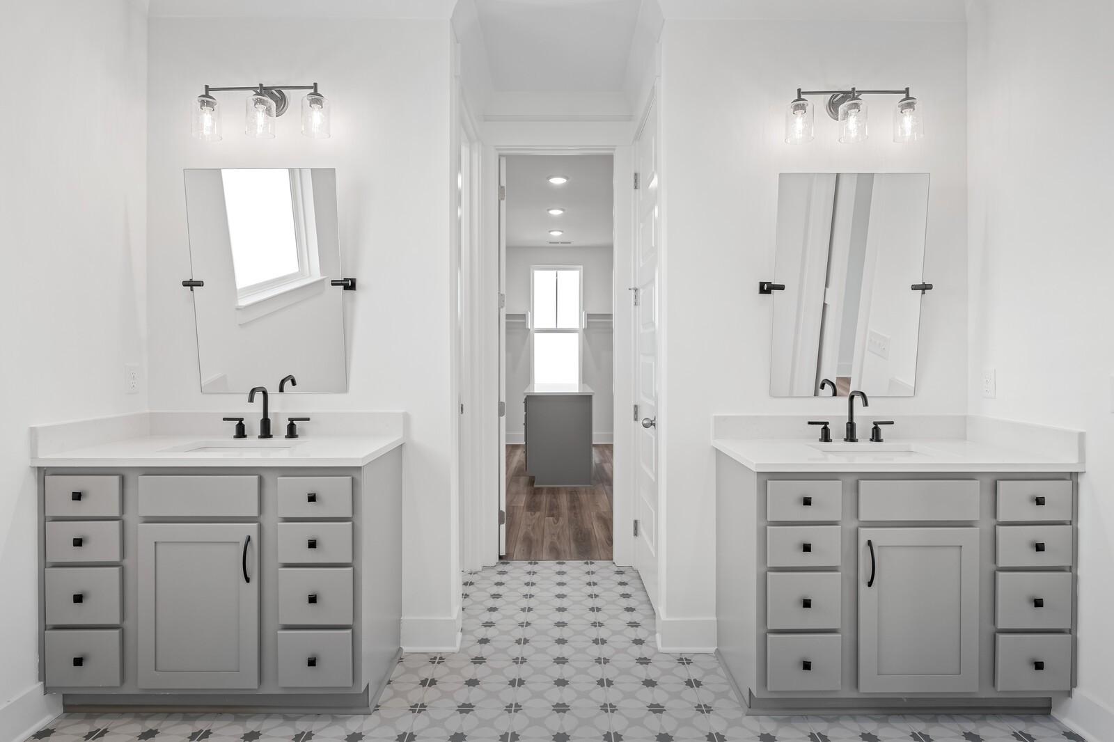 Modern double vanity bathroom with gray shaker cabinets, white quartz counters, framed mirrors, and patterned tile floor in The Alston A, Murfreesboro, TN