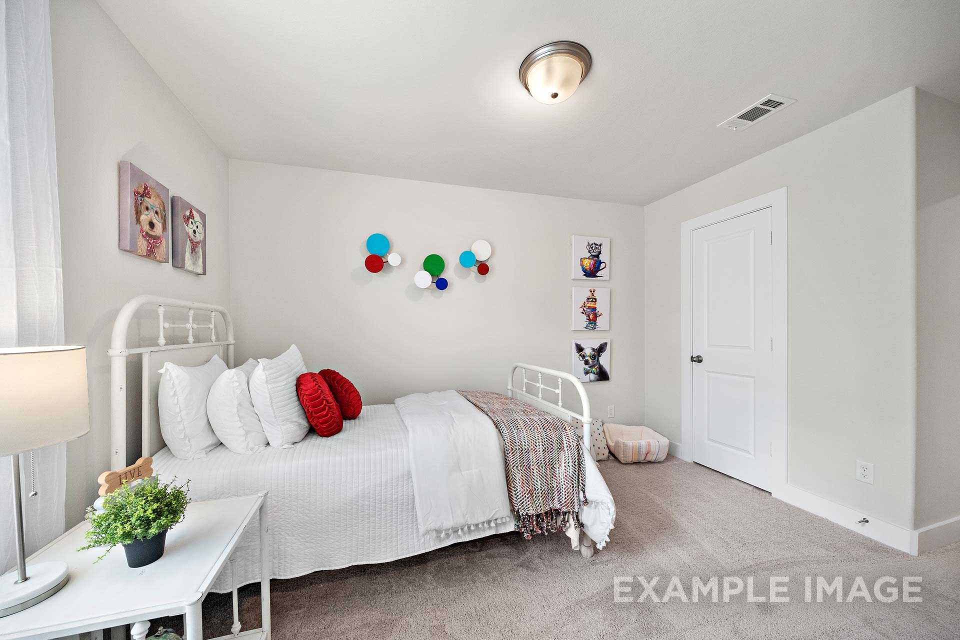 Charming child's bedroom in The Lily A with white twin bed, red pillows, dog-themed wall art, and colorful accents