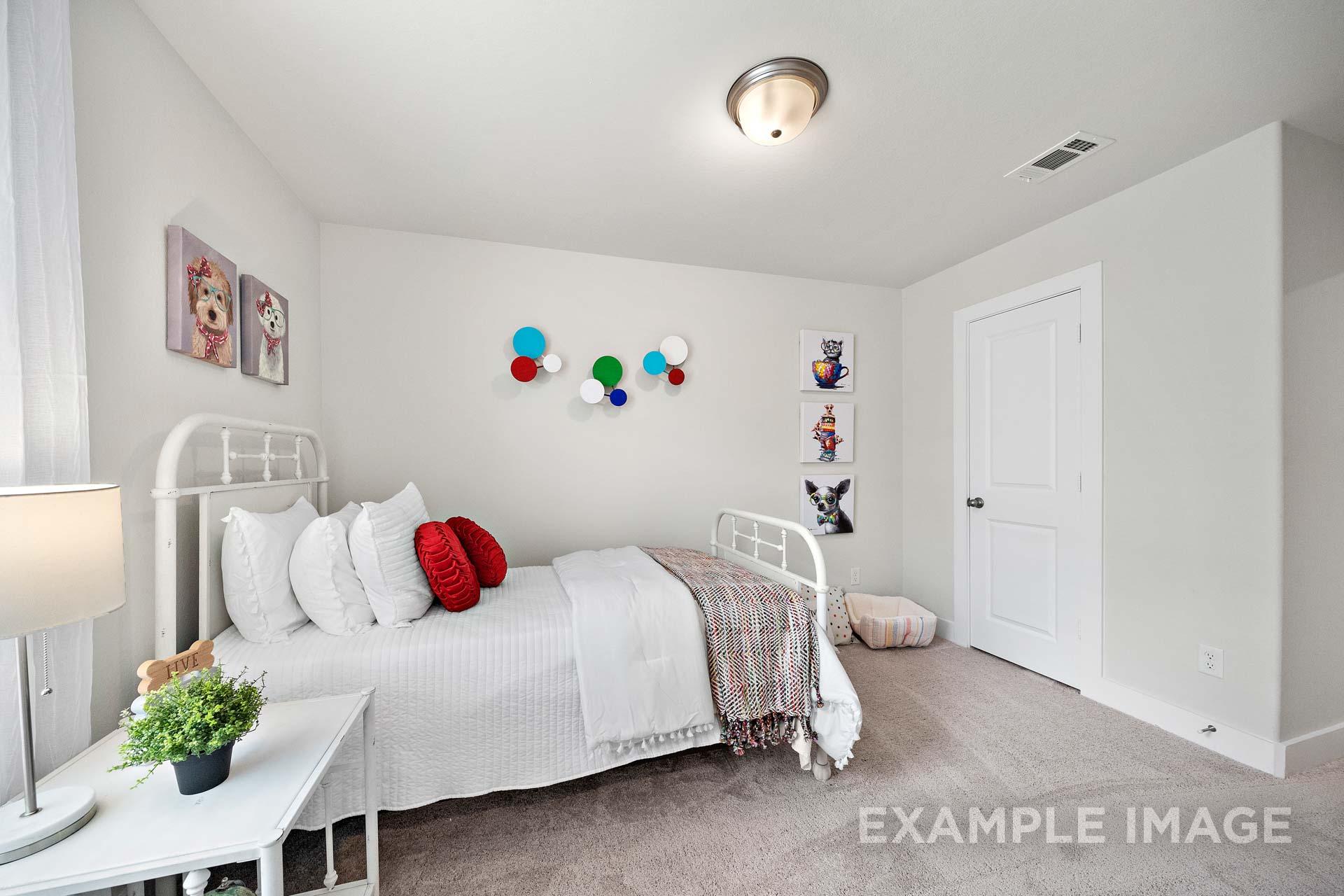 Charming child's bedroom in The Lily A with white twin bed, red pillows, dog-themed wall art, and colorful accents