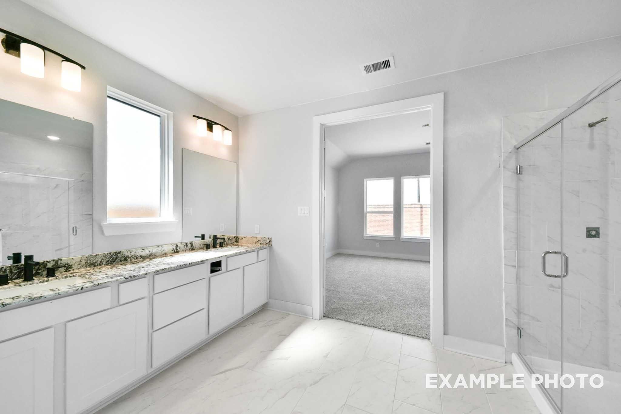 Modern master bathroom with double vanity, granite counters, white cabinets, and frameless glass shower in Davidson Homes The George A, Lago Mar, Texas City