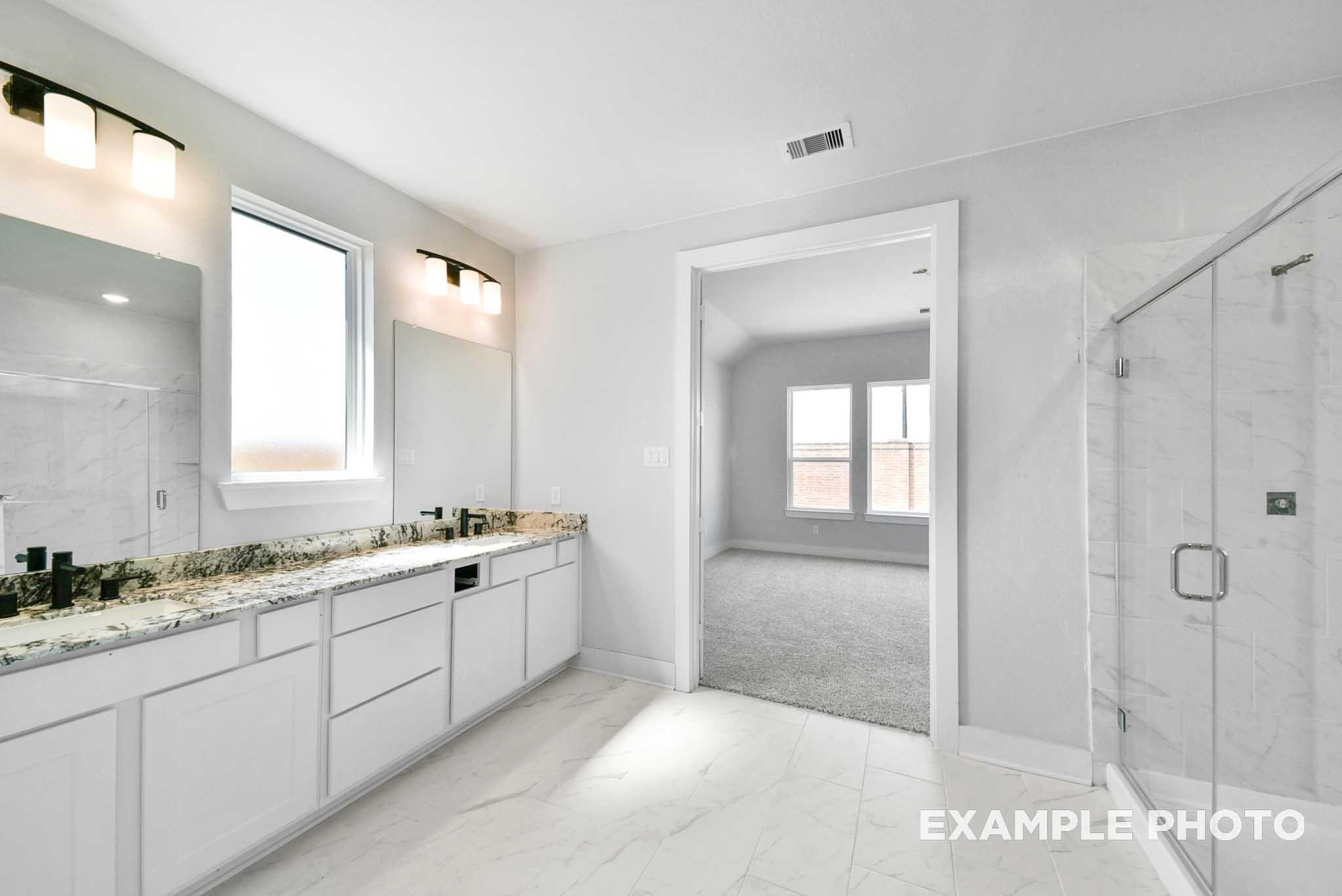 Modern master bathroom with double vanity, granite counters, white cabinets, and frameless glass shower in Davidson Homes The George A, Lago Mar, Texas City
