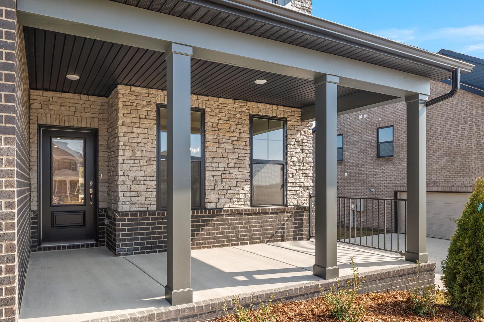 Covered front porch with stone and brick facade, black door, and columns on Davidson Homes Willow D in Mt. Juliet, TN