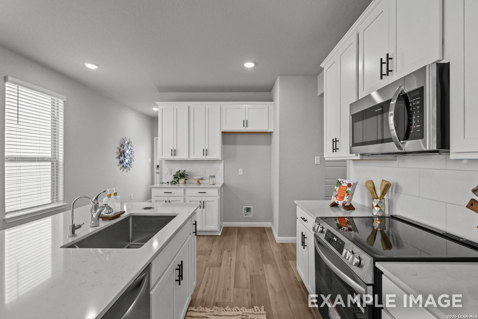 Modern kitchen with white cabinets, quartz countertops, and stainless appliances in The Gillian D, Cedar Heights home.