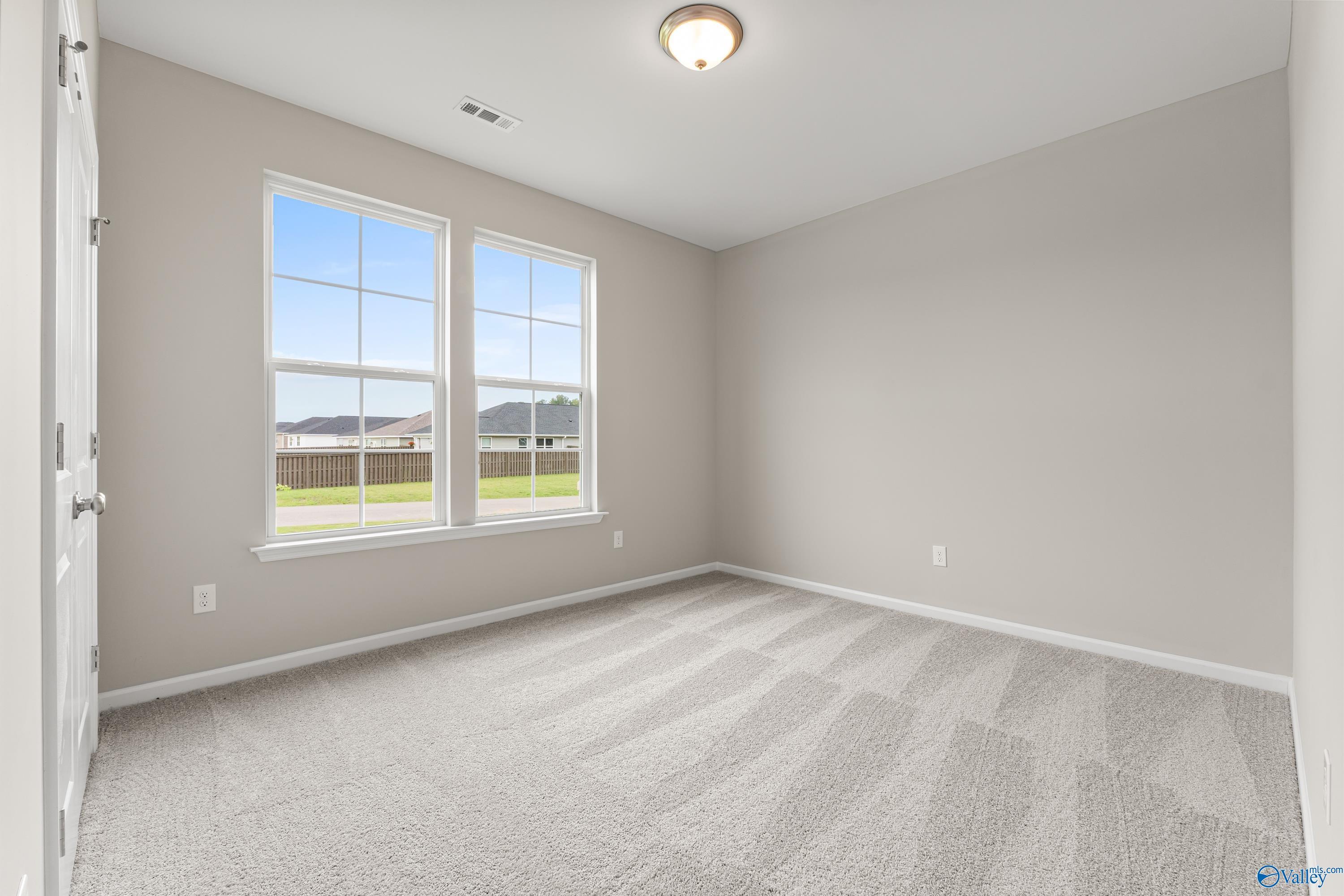 Bright secondary bedroom with beige walls, large windows, and field view in Davidson Homes The Phoenix, Fayetteville, TN