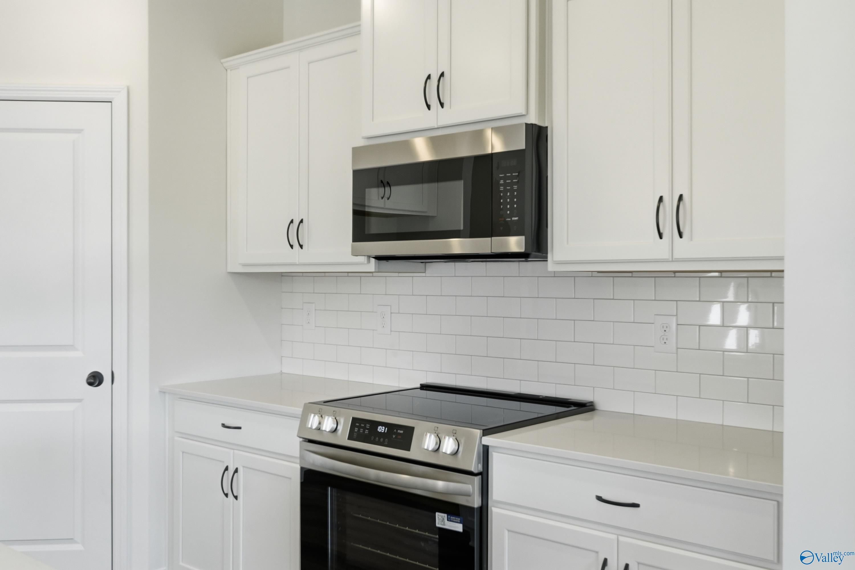Modern kitchen featuring white shaker cabinets, stainless steel microwave, oven, and subway tile backsplash in Davidson Homes The Franklin C, New Market, AL