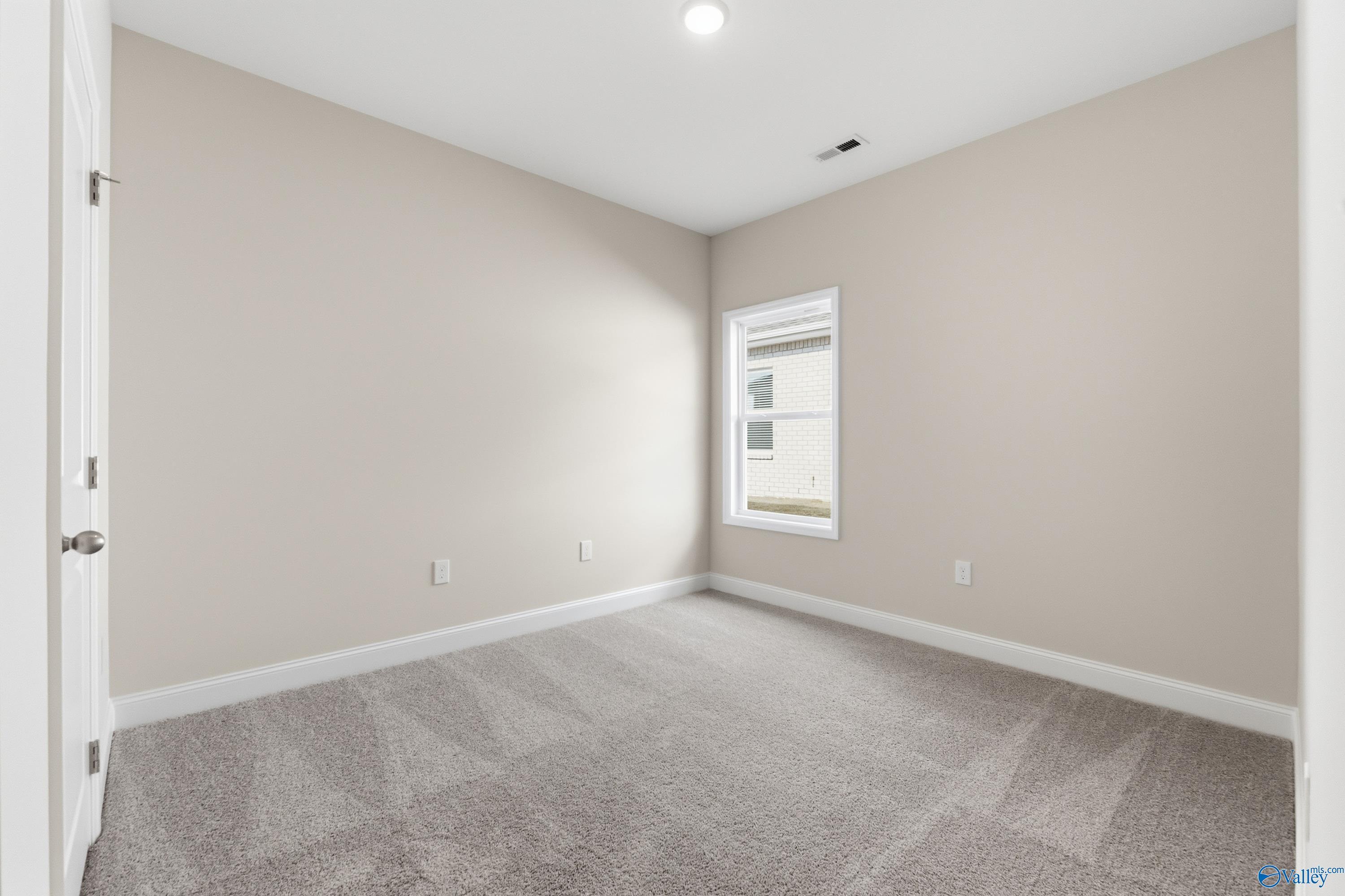 Bright secondary bedroom with beige walls, gray carpet, and window in Davidson Homes The Asheville C, Jaguar Hills, Huntsville