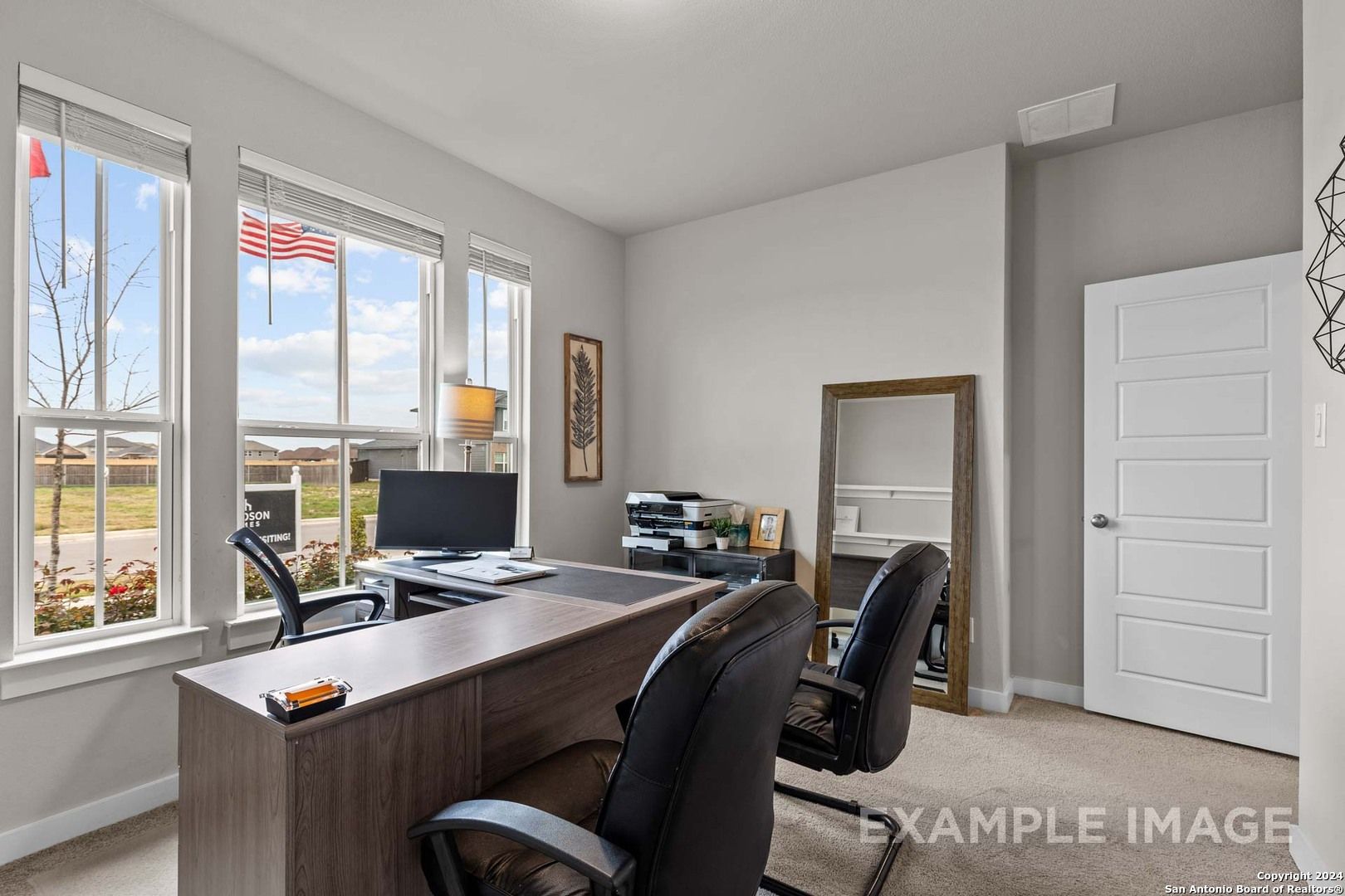 Bright home office with large windows, executive desk, leather chairs, and mirror in Davidson Homes The Collin A, Seguin, Texas