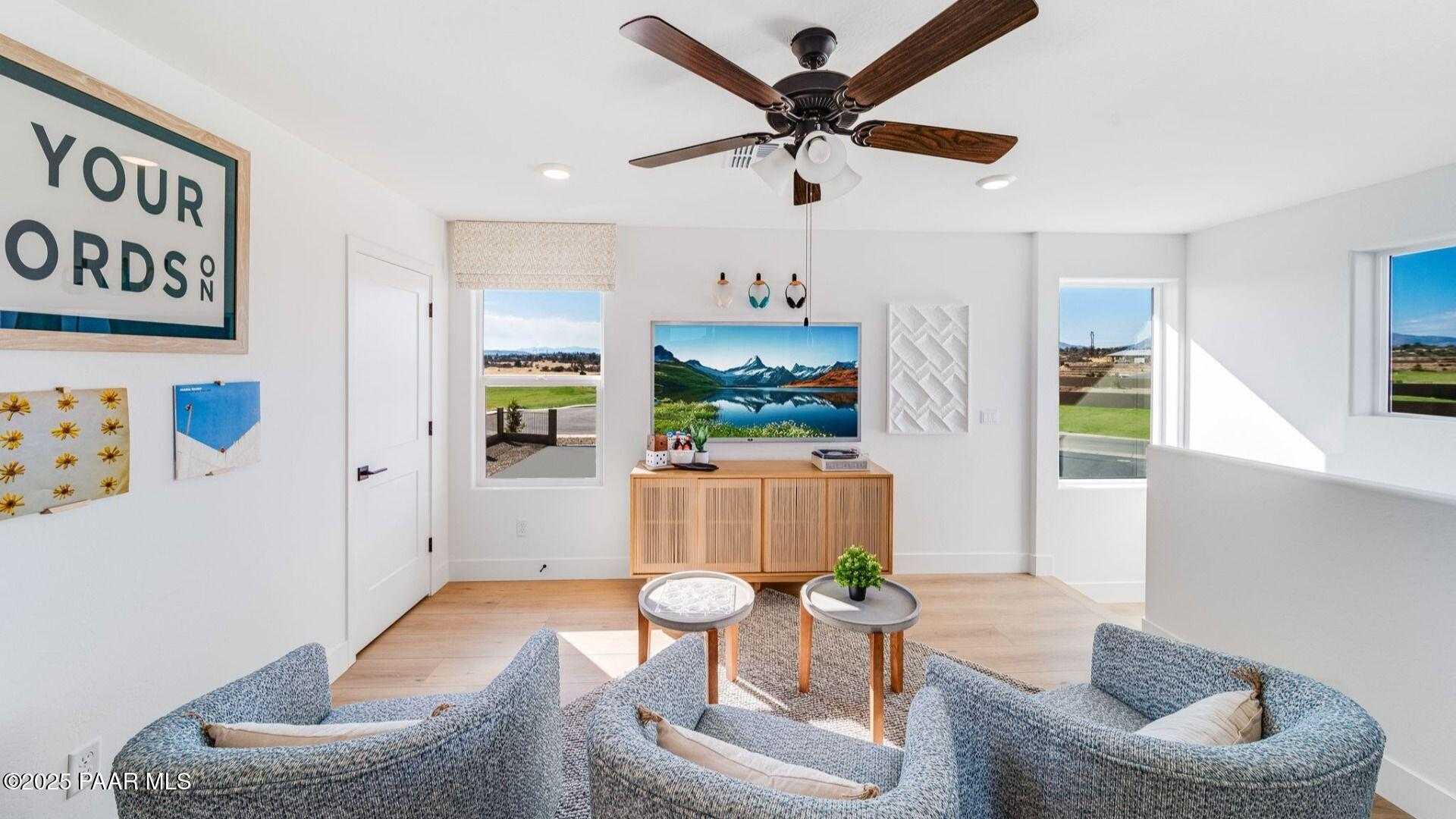 Cozy upstairs loft with gray armchairs, ceiling fan, scenic views through large windows in The Wilmington B, Prescott Arizona