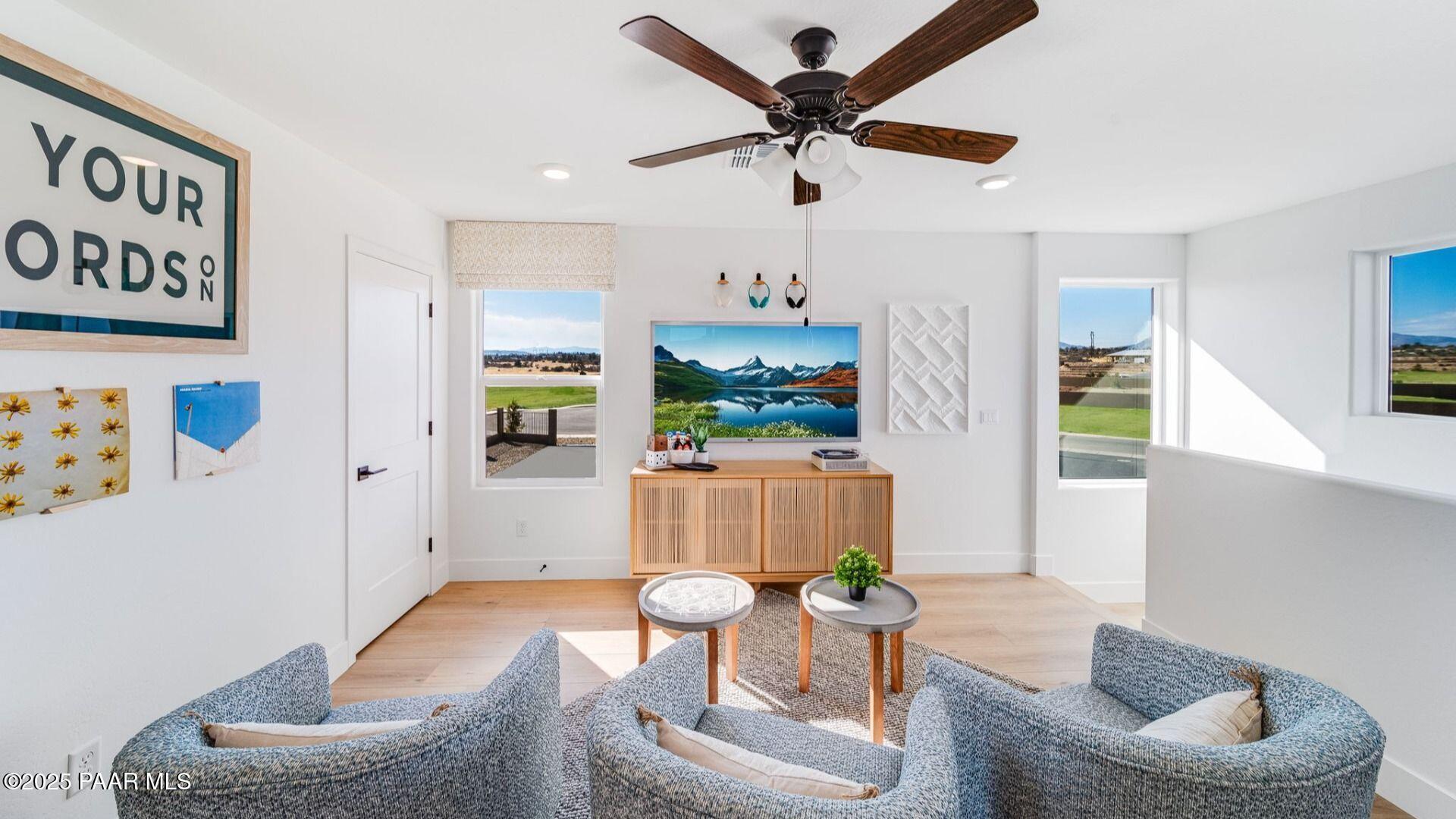 Cozy upstairs loft with gray armchairs, ceiling fan, scenic views through large windows in The Wilmington B, Prescott Arizona
