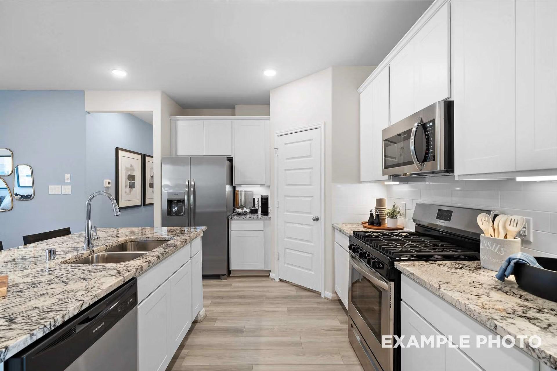 Modern kitchen with granite countertops, white cabinets, and stainless steel appliances in The San Marcos E floor plan.
