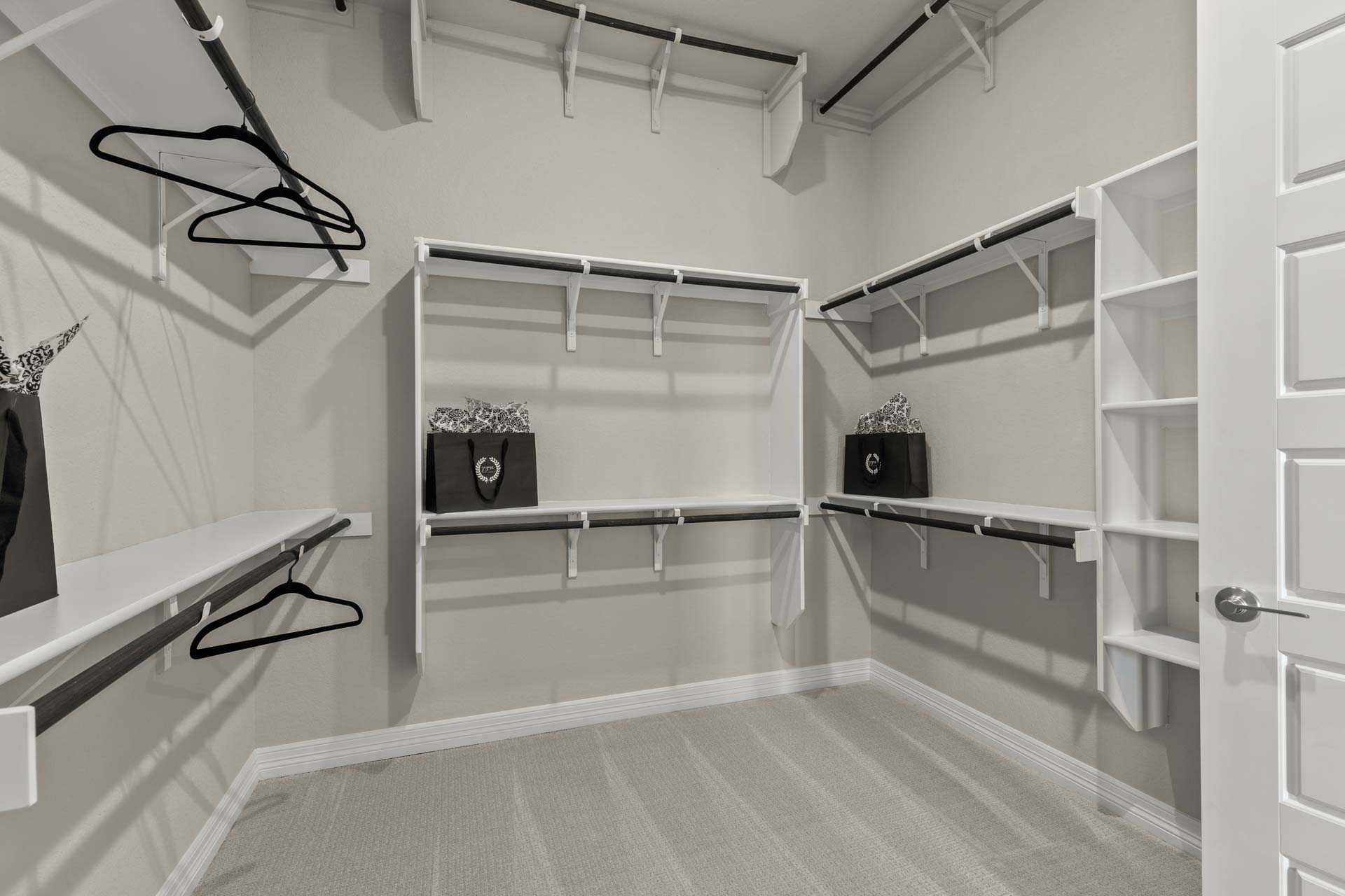 Spacious walk-in closet in The Summerlin B with white built-in shelving, hanging rods, and organized storage