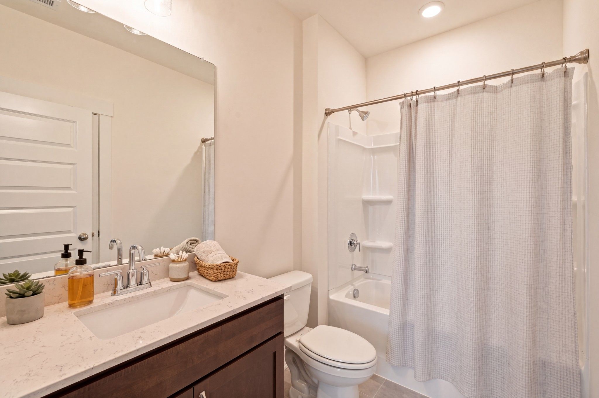 Bright full bathroom with quartz vanity, tub shower, and white toilet in Davidson Homes The Willow C, Woods Crossing, Gallatin TN
